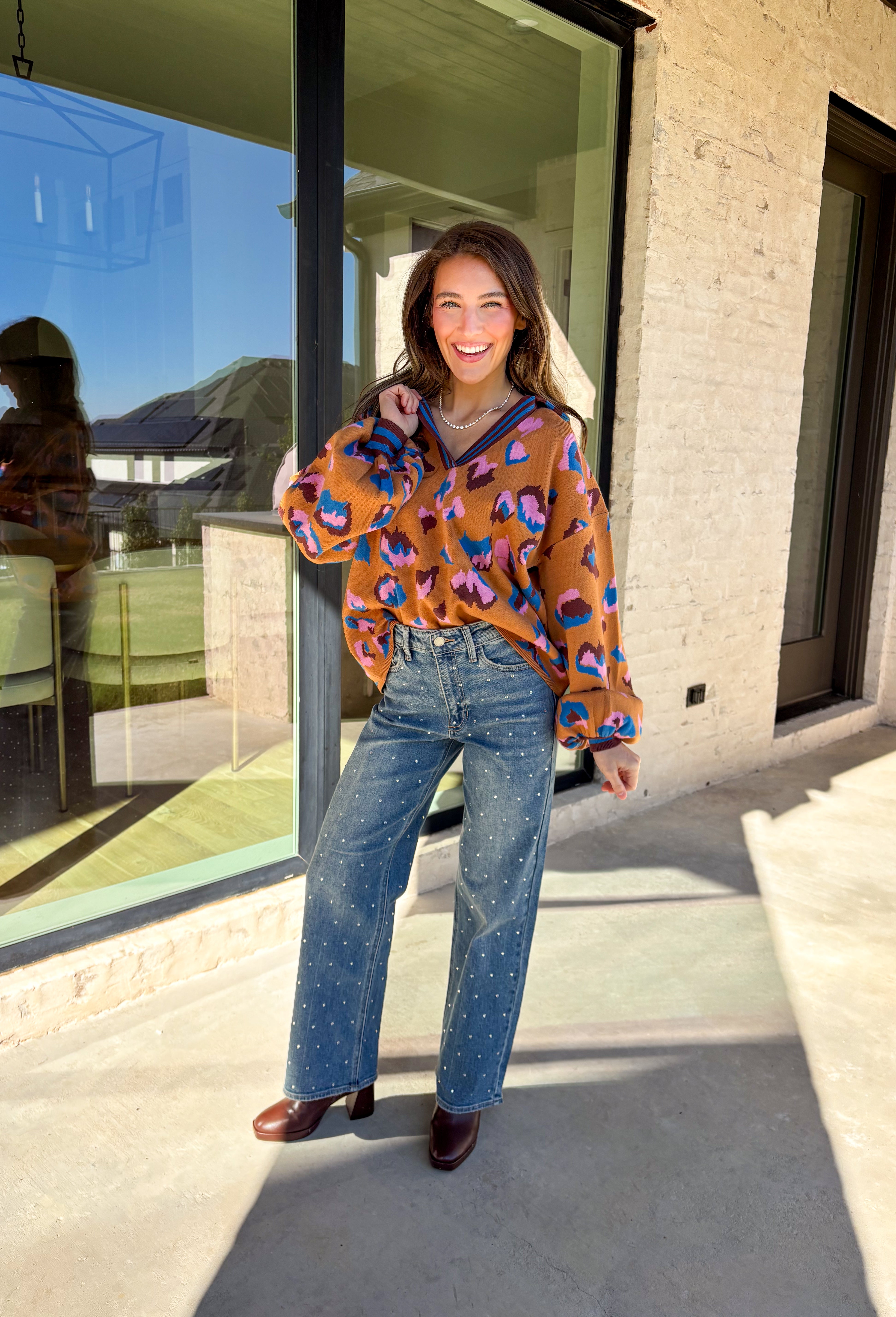 Brighten up your winter wardrobe with this bold camel sweater by Fate, featuring an eye-catching leopard print in shades of brown, pink, and blue. The striped collar and neckline add a fun, sporty touch while the soft knit keeps things cozy and comfortable for chilly days. It’s the perfect statement sweater for adding color and personality to your cold-weather lineup.