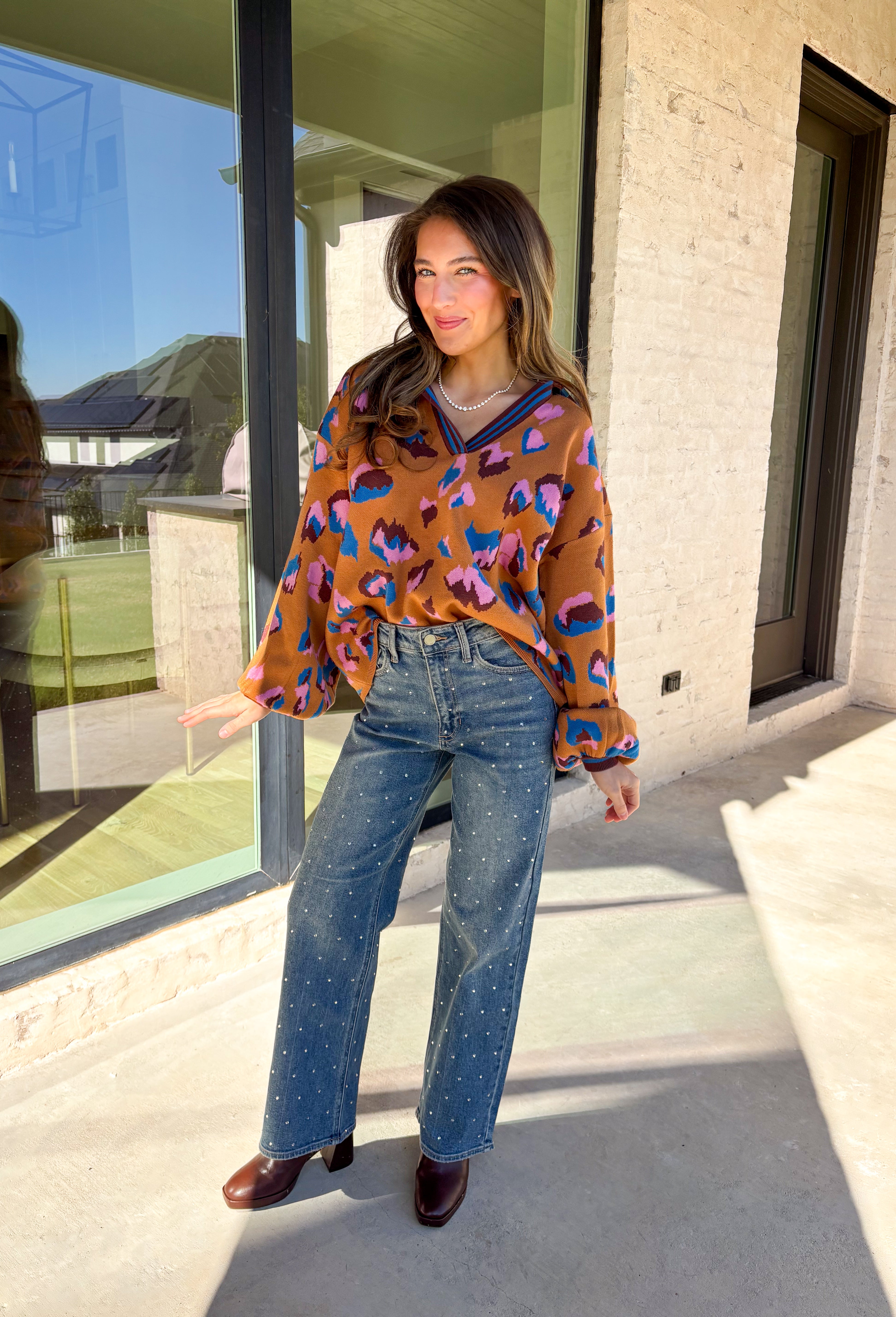 Brighten up your winter wardrobe with this bold camel sweater by Fate, featuring an eye-catching leopard print in shades of brown, pink, and blue. The striped collar and neckline add a fun, sporty touch while the soft knit keeps things cozy and comfortable for chilly days. It’s the perfect statement sweater for adding color and personality to your cold-weather lineup.