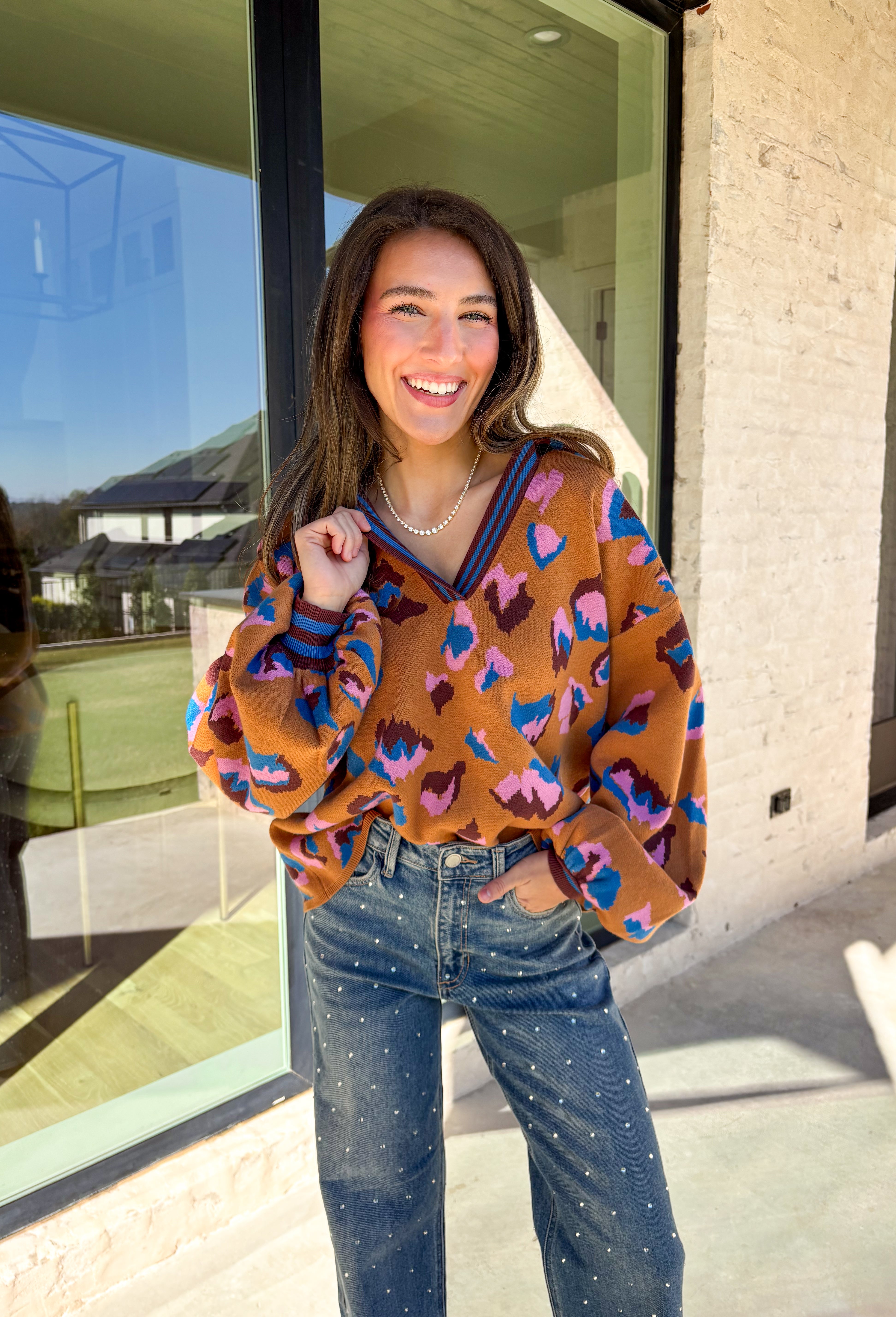Brighten up your winter wardrobe with this bold camel sweater by Fate, featuring an eye-catching leopard print in shades of brown, pink, and blue. The striped collar and neckline add a fun, sporty touch while the soft knit keeps things cozy and comfortable for chilly days. It’s the perfect statement sweater for adding color and personality to your cold-weather lineup.