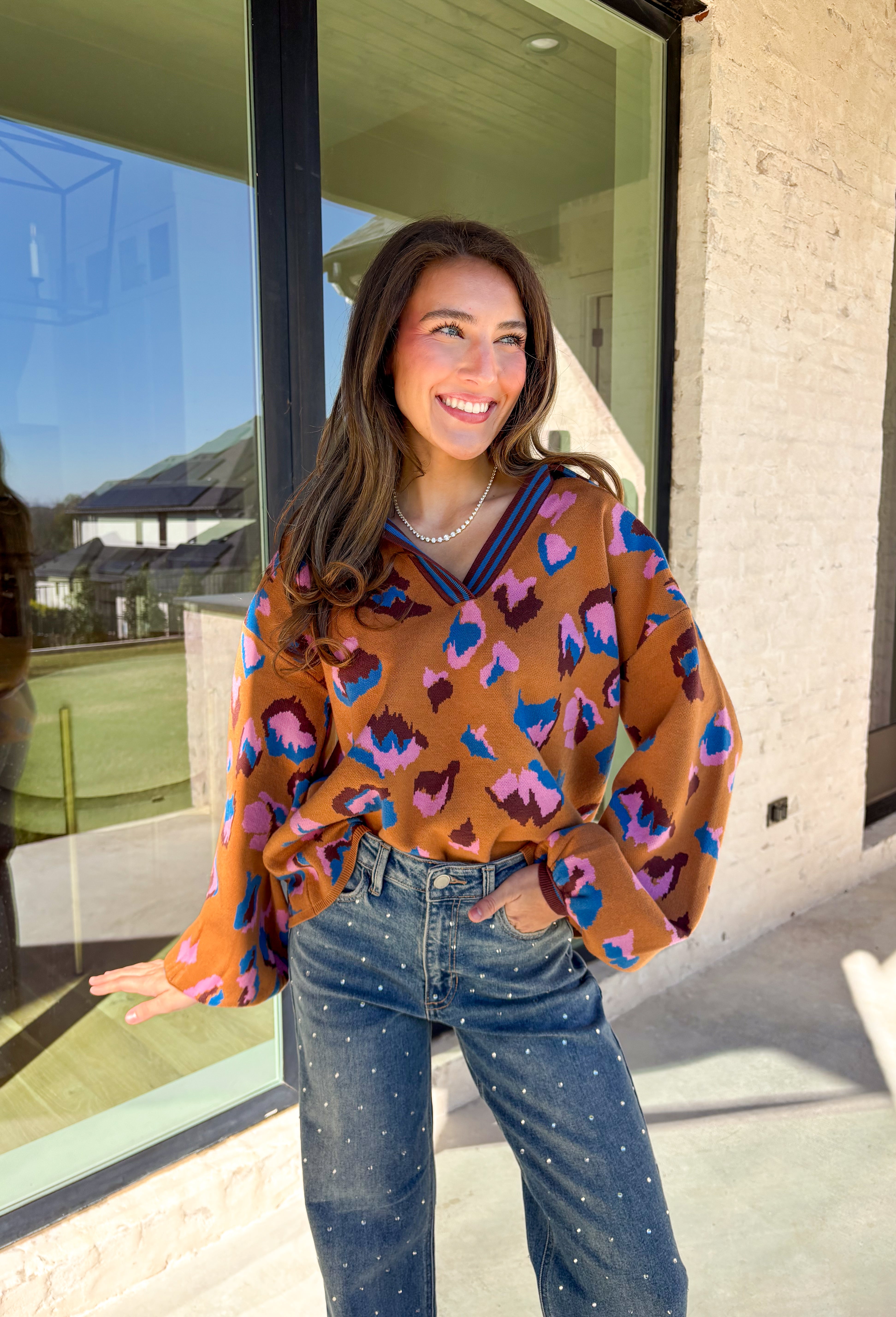 Brighten up your winter wardrobe with this bold camel sweater by Fate, featuring an eye-catching leopard print in shades of brown, pink, and blue. The striped collar and neckline add a fun, sporty touch while the soft knit keeps things cozy and comfortable for chilly days. It’s the perfect statement sweater for adding color and personality to your cold-weather lineup.