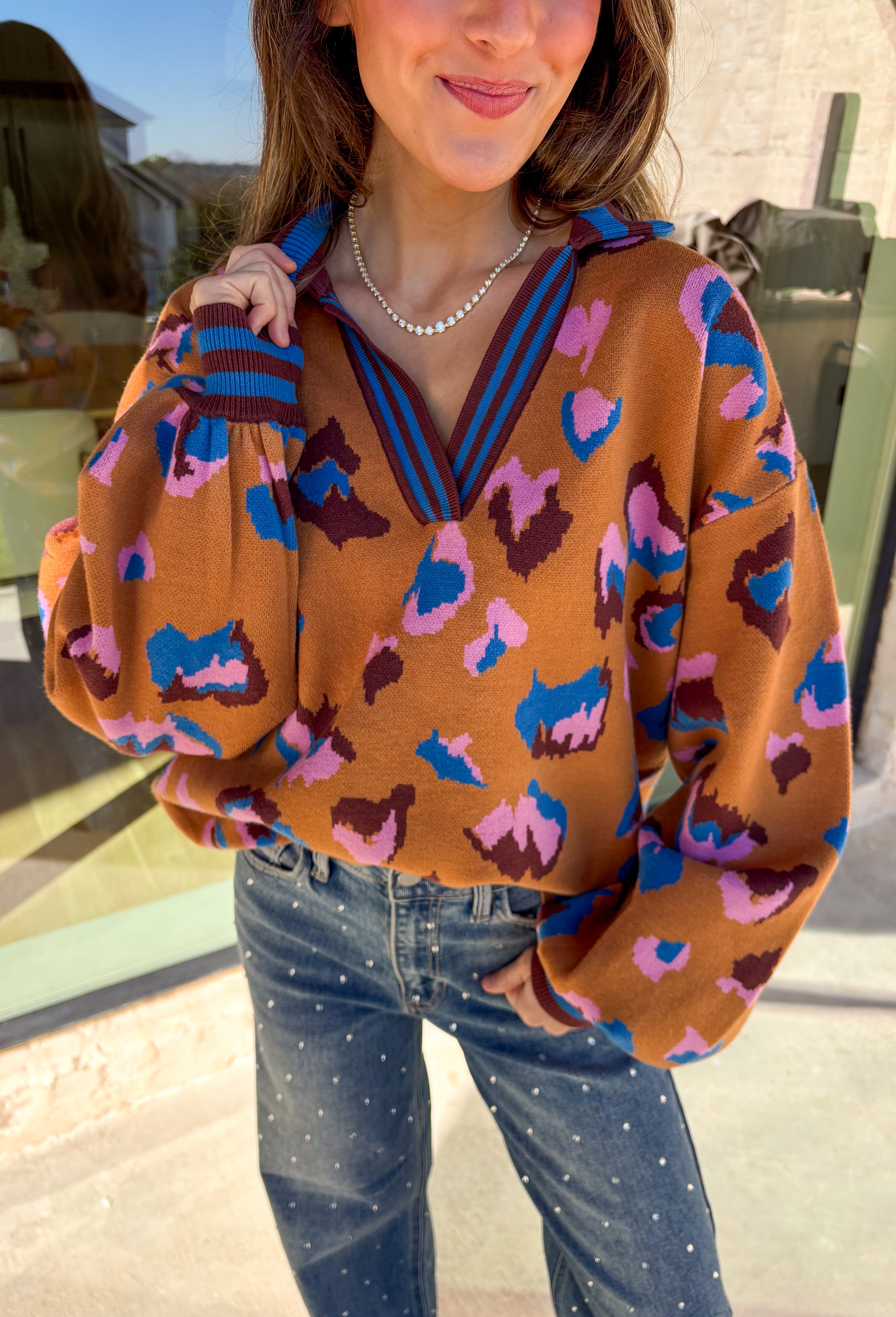 Brighten up your winter wardrobe with this bold camel sweater by Fate, featuring an eye-catching leopard print in shades of brown, pink, and blue. The striped collar and neckline add a fun, sporty touch while the soft knit keeps things cozy and comfortable for chilly days. It’s the perfect statement sweater for adding color and personality to your cold-weather lineup.