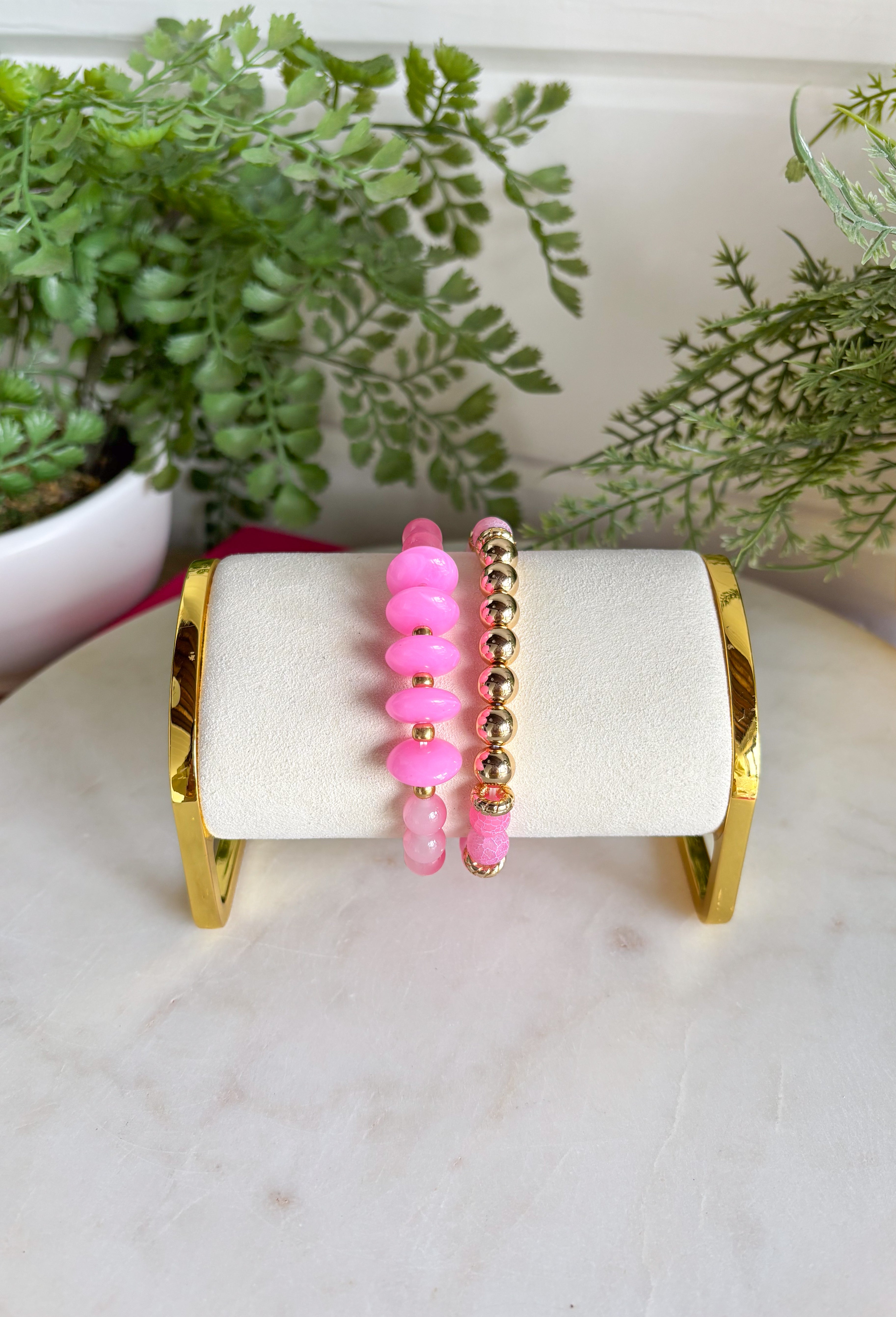 This pink and gold beaded bracelet set is the easiest way to add a fun pop of color to your summer look! Featuring two unique bracelets with a mix of textures and bead sizes, they create that perfectly layered, effortless stack without any extra work. The soft pink tones paired with gold accents feel fresh, playful, and easy to style with everything from casual outfits to dressier looks. Just slip them on and go—they’re made for sunny days, vacations, and everyday wear. 