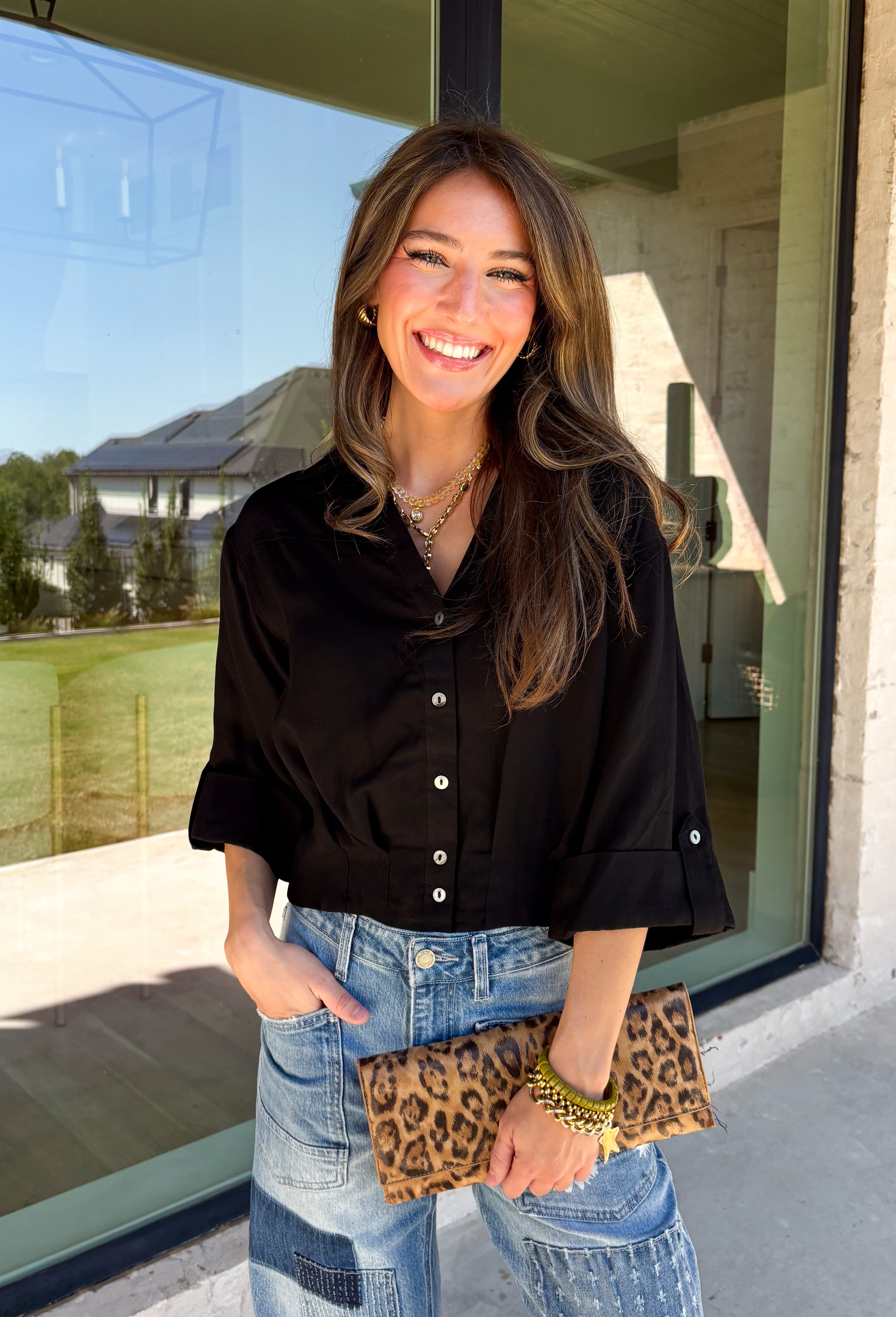 Every wardrobe needs a timeless black blouse, and this versatile top from Entro is one you'll reach for again and again. Designed with a flattering v-neckline and button-front closure, this effortlessly polished piece transitions seamlessly from workdays to weekends. The ¾ roll-tab sleeves offer versatile styling, while the elasticized smocked back hem creates a comfortable fit with a modern touch. 