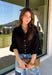 Every wardrobe needs a timeless black blouse, and this versatile top from Entro is one you'll reach for again and again. Designed with a flattering v-neckline and button-front closure, this effortlessly polished piece transitions seamlessly from workdays to weekends. The ¾ roll-tab sleeves offer versatile styling, while the elasticized smocked back hem creates a comfortable fit with a modern touch. 