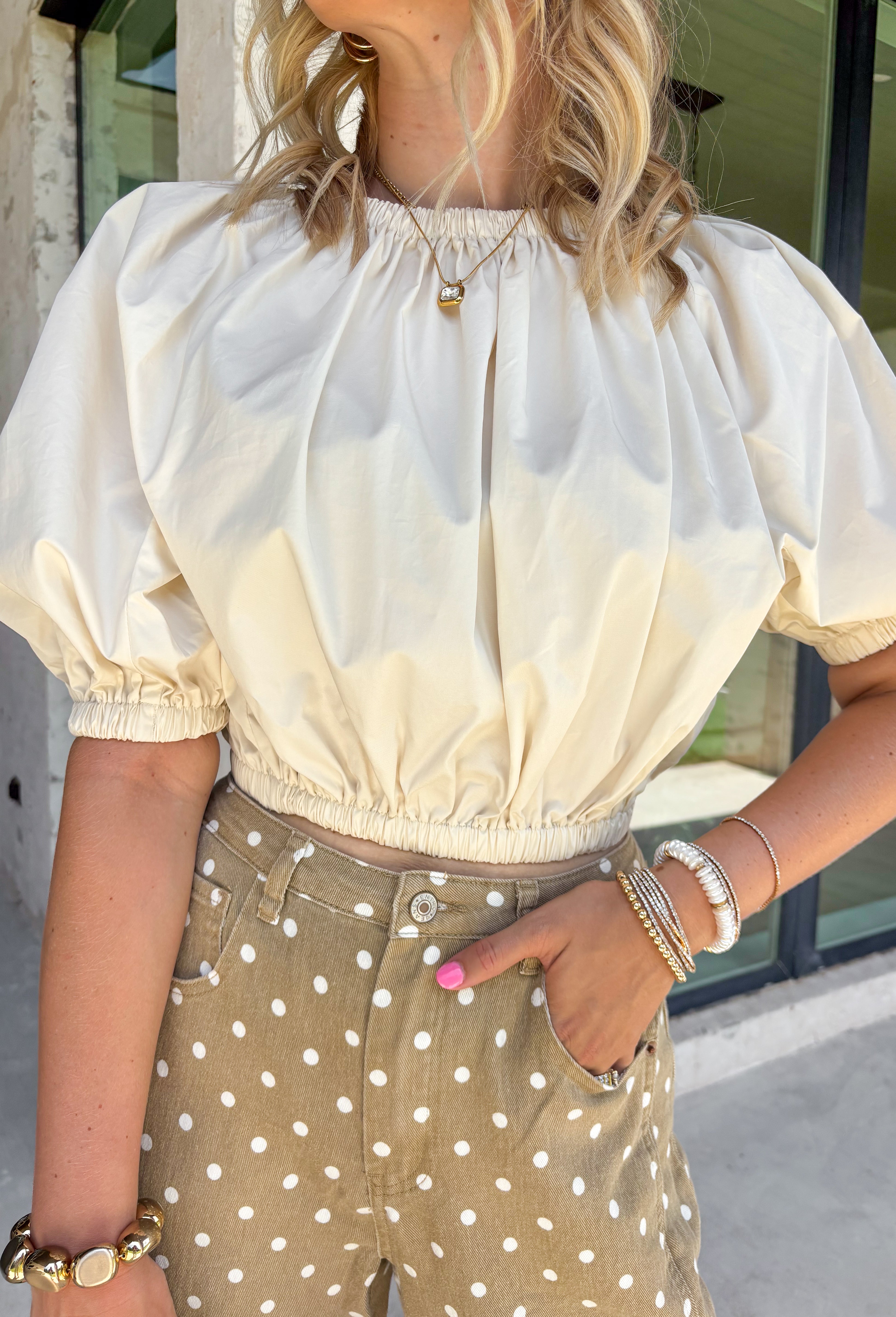 This cream cotton top is the definition of effortless fall style! Designed with a versatile elastic neckline, you can wear it on or off the shoulders depending on your mood and the occasion. The relaxed silhouette is finished with an elastic hem and gathered cuffs, creating a flattering shape that's equal parts comfortable and chic. Crafted from breathable cotton, it's perfect for those crisp autumn afternoons and layers beautifully with your favorite denim jacket or cardigan. 