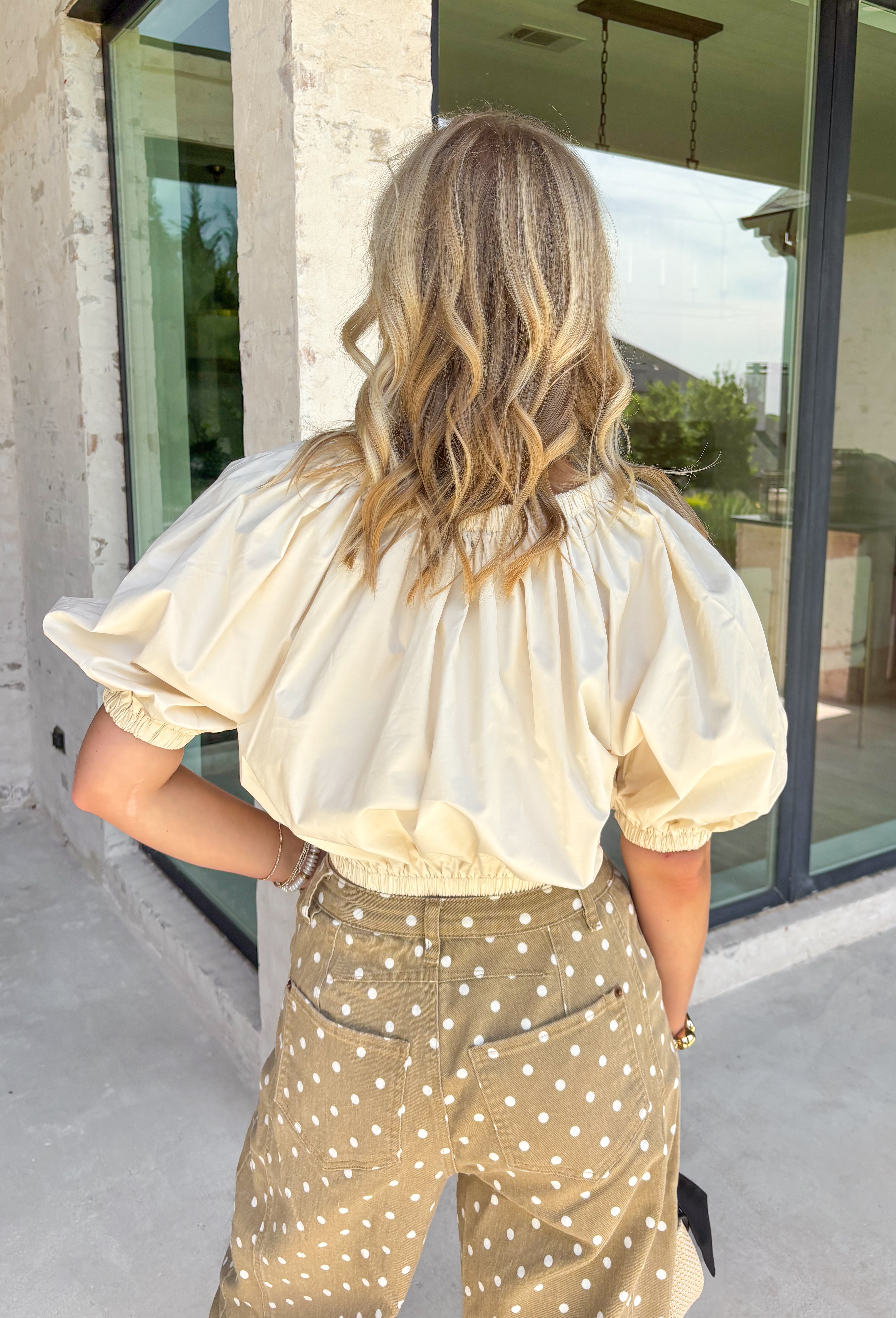 This cream cotton top is the definition of effortless fall style! Designed with a versatile elastic neckline, you can wear it on or off the shoulders depending on your mood and the occasion. The relaxed silhouette is finished with an elastic hem and gathered cuffs, creating a flattering shape that's equal parts comfortable and chic. Crafted from breathable cotton, it's perfect for those crisp autumn afternoons and layers beautifully with your favorite denim jacket or cardigan. 