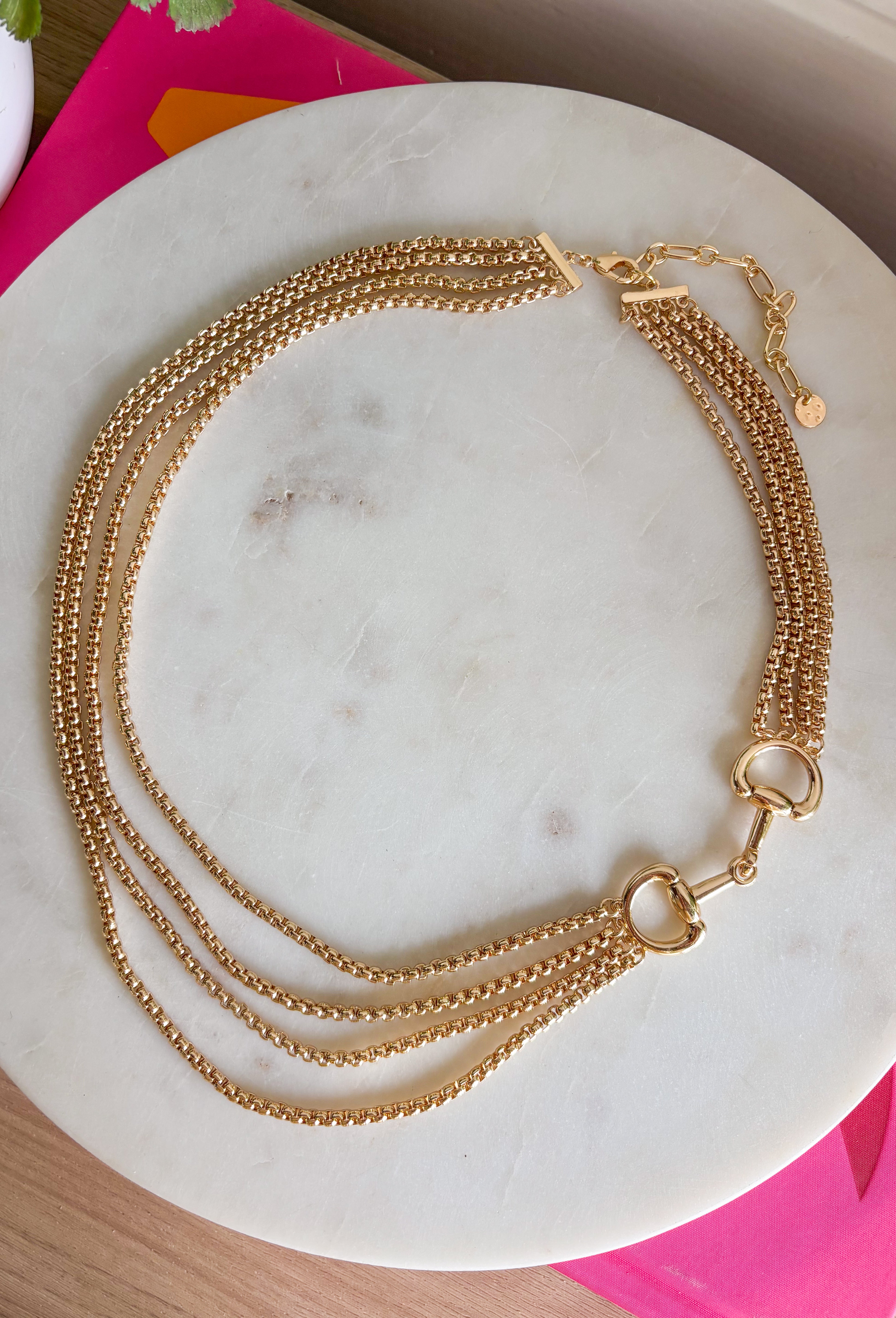This gold layered chain necklace with a horse bit detail is the perfect blend of trendy and timeless for summer styling! The layered look gives you that effortlessly styled feel without the extra work, while the horse bit detail adds a classic, elevated touch. At 19.5" in length, it sits perfectly to make a statement on its own or pair with shorter chains for a stacked look. Whether you're dressing up a simple tank or adding polish to a breezy dress, this piece pulls everything together. 