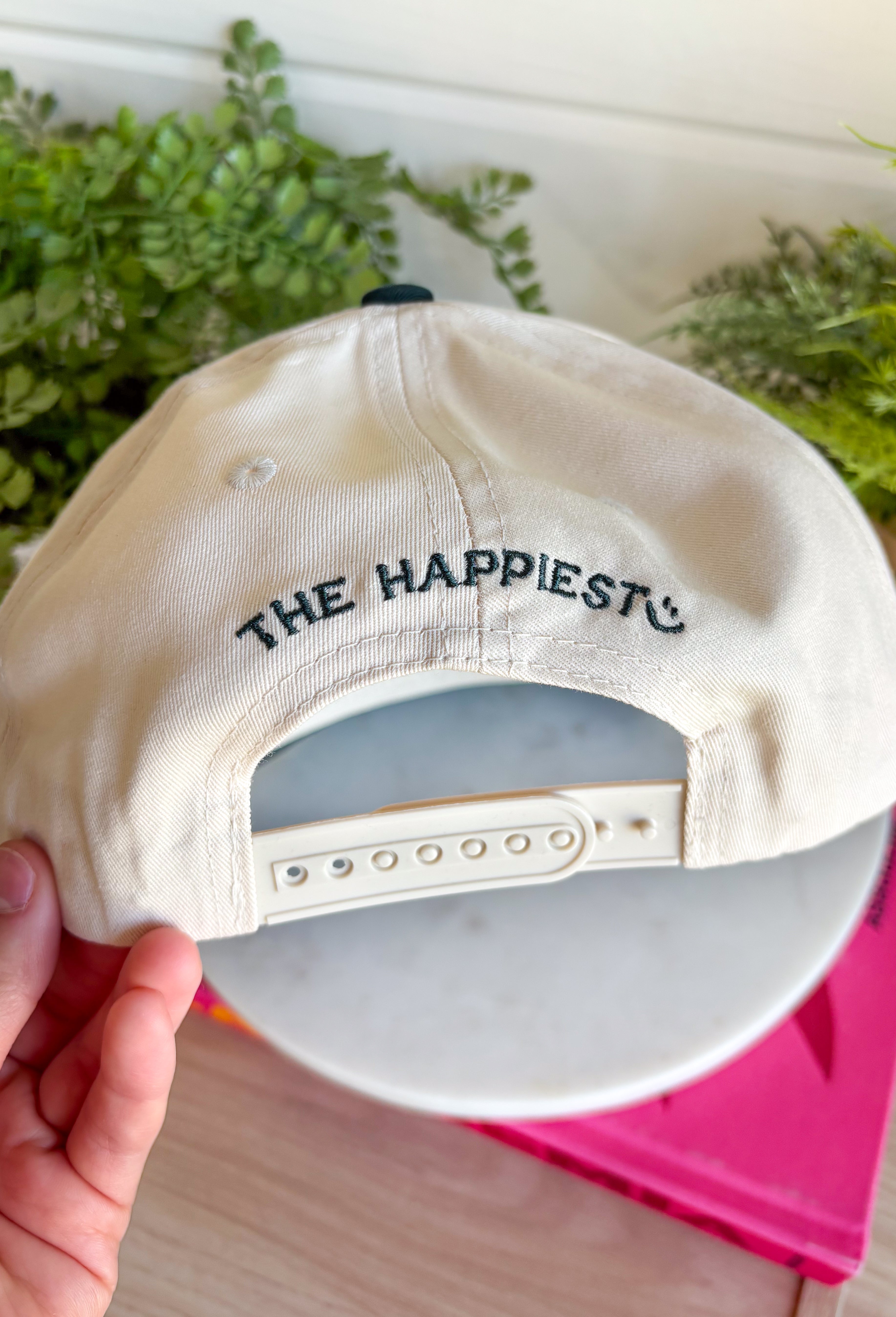 Whether you're headed to the lake, spending the day outdoors, or just love a playful graphic accessory, this trucker hat from The Happiest is the perfect finishing touch. Featuring a neutral crown with a hunter green bill, this hat is embroidered with "Today's Catch" and a colorful fish design in shades of green, blue, and pink for a fun, laid-back look. The adjustable fit makes it comfortable for all-day wear, making it an easy grab-and-go accessory for every adventure.