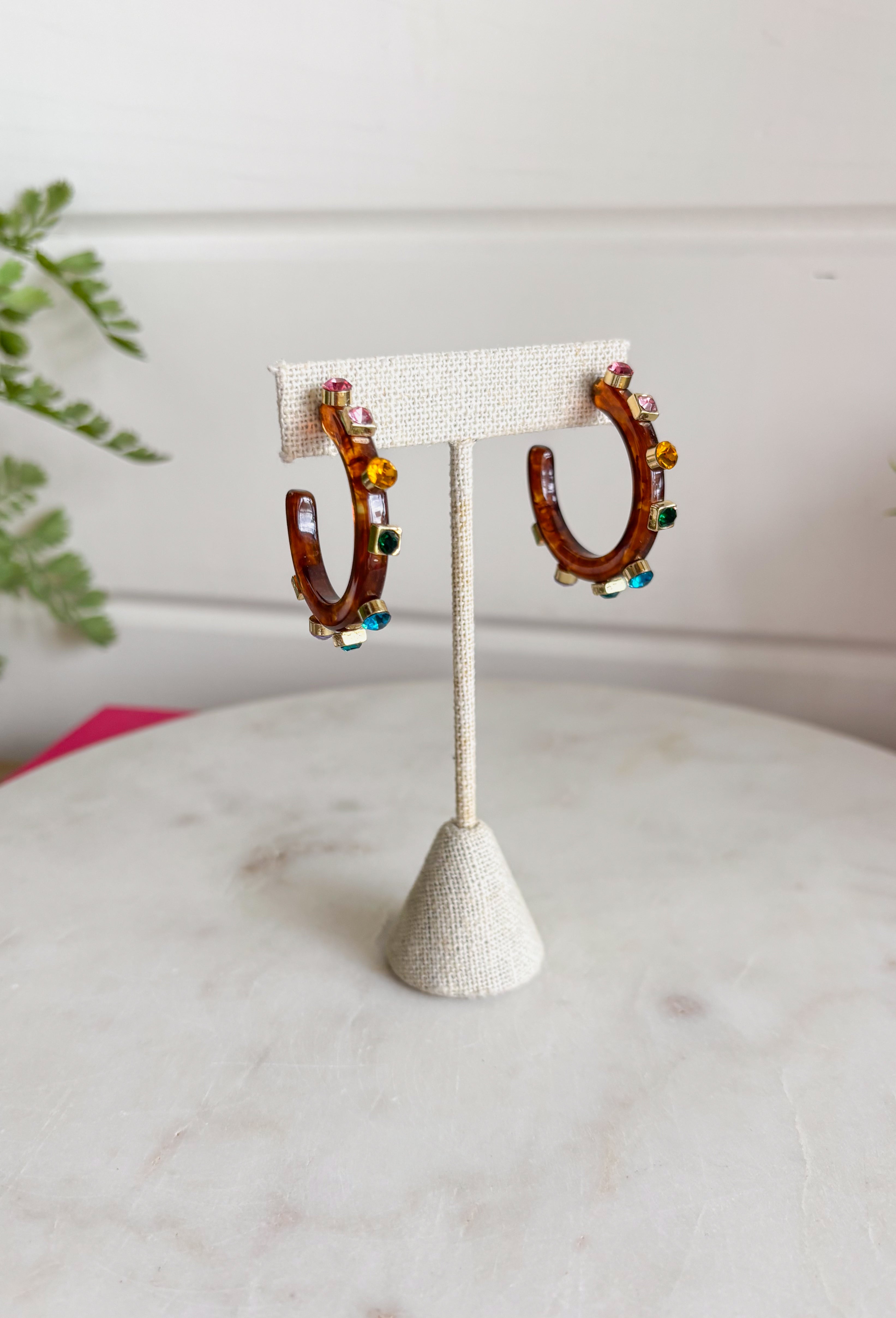 A little sparkle and a lot of personality! These glossy tortoise earrings are the perfect mix of classic and colorful. Designed with vibrant jewel-tone crystals, they add the prettiest pop of color while the tortoise finish keeps the look timeless and easy to style. Lightweight and fun to wear, these earrings instantly elevate any outfit—from casual daytime looks to dressier evenings out. The bold color and shine make them an effortless statement piece you'll reach for again and again.