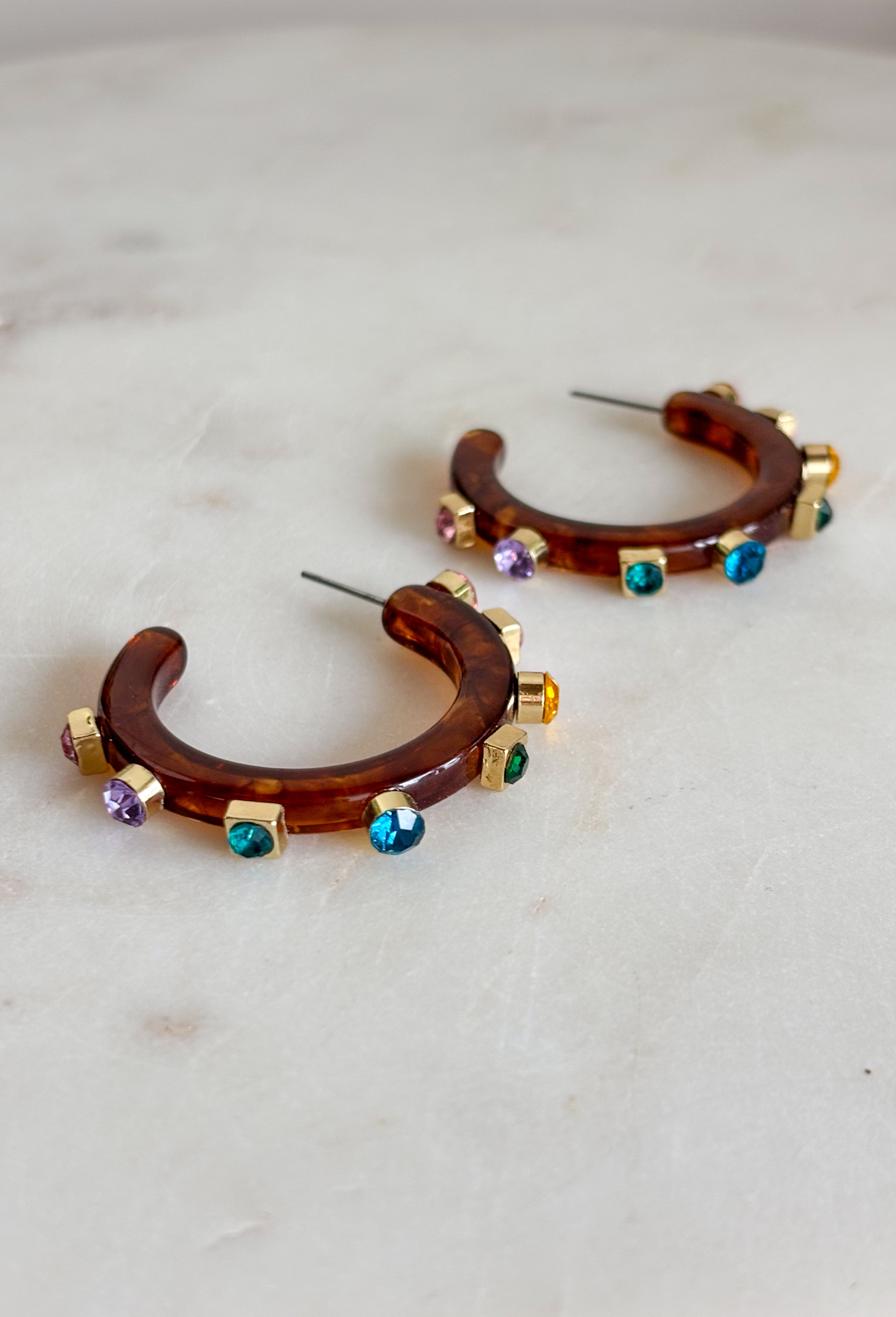 A little sparkle and a lot of personality! These glossy tortoise earrings are the perfect mix of classic and colorful. Designed with vibrant jewel-tone crystals, they add the prettiest pop of color while the tortoise finish keeps the look timeless and easy to style. Lightweight and fun to wear, these earrings instantly elevate any outfit—from casual daytime looks to dressier evenings out. The bold color and shine make them an effortless statement piece you'll reach for again and again.