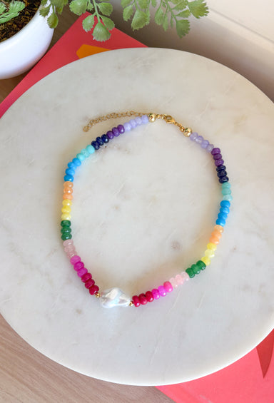This colorful gemstone beaded necklace is pure happiness in accessory form! Featuring a mix of purple, blue, orange, yellow, green, and pink with a pearl accent, it adds the perfect playful pop to all your summer outfits. It’s bright, fun, and instantly makes even the simplest look feel styled. The shorter length sits perfectly at the neckline, making it great for layering or wearing solo as a statement.