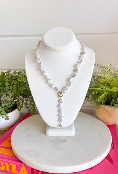 Classic pearls meet modern elegance in this stunning lariat necklace! Featuring lustrous pearls and a chic gold toggle closure, this timeless piece is finished with a sparkling rhinestone accent that adds just the right amount of shimmer. Whether you're dressing up for a holiday celebration, wedding, date night, or simply elevating your everyday style, this handcrafted necklace brings effortless sophistication to any outfit.