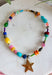 Color, texture, and a little golden shine come together in this playful necklace from Treasure Jewels. A dazzling mix of yellow, pink, blue, green, orange, gold, and spotted beads gives it a collected, one-of-a-kind feel, while the variety of shapes and textures makes every detail worth a closer look. A gold star pendant finishes the design with a fun statement at the center. Whether you’re brightening up a simple sweater or adding extra personality to a layered look, this necklace is made to stand out.