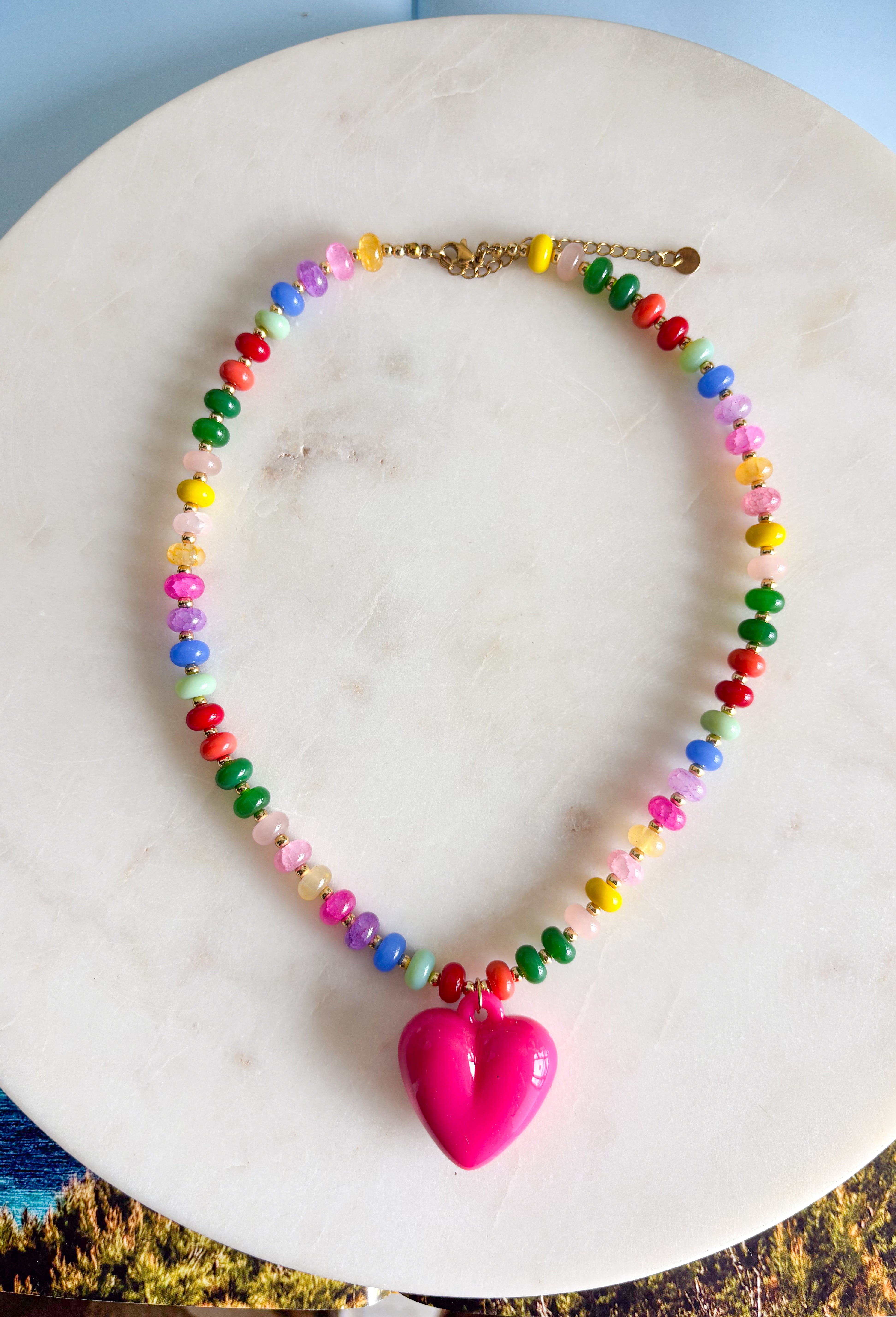 Bright, playful, and full of personality! This colorful beaded necklace is the perfect piece to add a little happiness to your look. Featuring a mix of vibrant beads and a bold hot pink pendant charm, it brings a fun pop of color that instantly livens up any outfit.&nbsp;The adjustable chain makes it easy to style at different lengths, whether worn on its own or layered with other favorites. Cheerful and eye-catching, this necklace is a simple way to add a little joy to your everyday style.