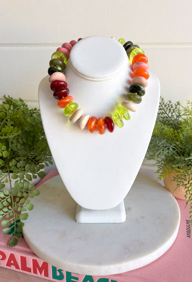 A multicolor beaded necklace displayed on a white jewelry bust