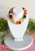 A multicolor beaded necklace displayed on a white jewelry bust