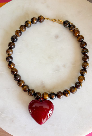 Rich natural tones and meaningful details make this handcrafted necklace a piece you'll treasure for years to come! Featuring genuine tiger eye natural stone beads, this beautiful necklace is finished with a striking burgundy heart pendant that adds the perfect pop of color. Whether worn alone or layered with your favorite chain, this timeless accessory effortlessly elevates everything from cozy sweaters to feminine dresses.