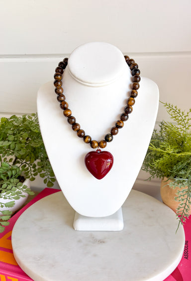 Rich natural tones and meaningful details make this handcrafted necklace a piece you'll treasure for years to come! Featuring genuine tiger eye natural stone beads, this beautiful necklace is finished with a striking burgundy heart pendant that adds the perfect pop of color. Whether worn alone or layered with your favorite chain, this timeless accessory effortlessly elevates everything from cozy sweaters to feminine dresses.