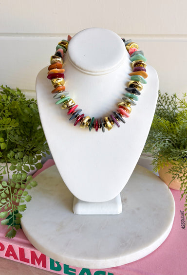 A colorful beaded necklace displayed on a white jewelry bust