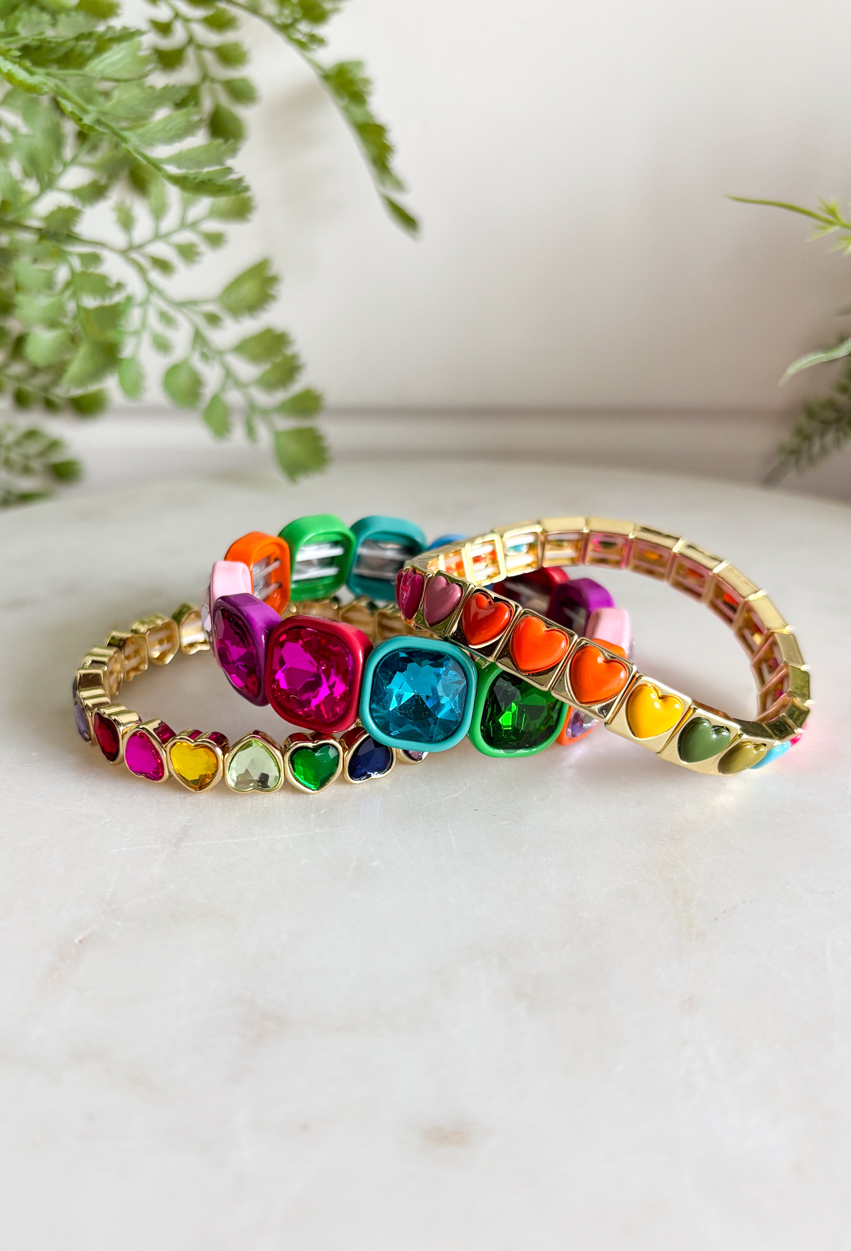 All the color, all the hearts, all the sparkle! This playful bracelet set is made to brighten your look with a vibrant mix of glossy heart tiles and oversized multi-color gemstone accents framed in warm gold tone settings. Each bracelet brings its own pop of color and shine, creating a fun, cheerful stack that instantly makes a statement.&nbsp;Designed to layer beautifully together, these bracelets create a bold, happy look when worn as a full stack. You can also mix and match them with your other favorites