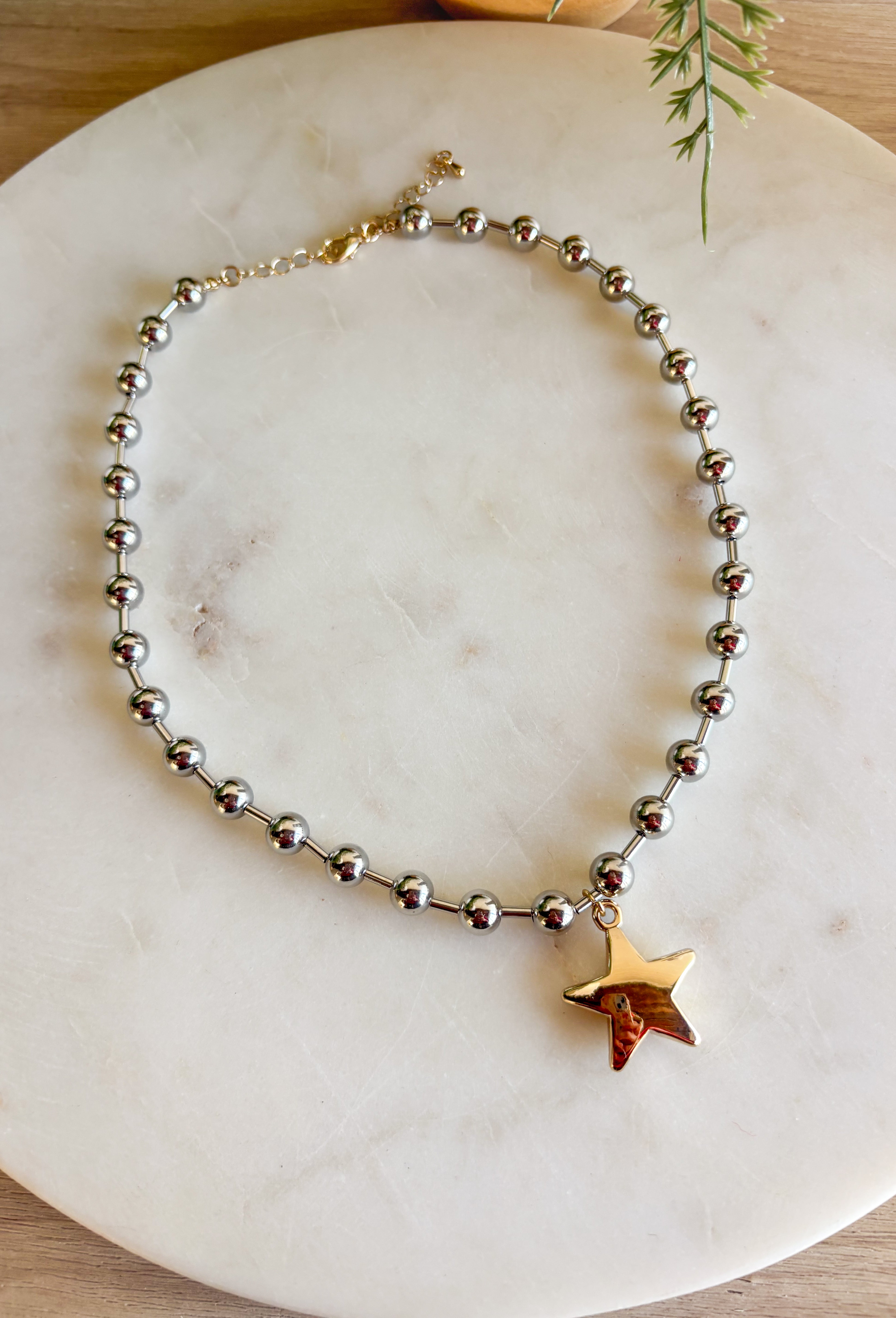 A versatile piece with just the right amount of presence—this silver beaded necklace is finished with a gold star charm that adds a modern, stylish touch. The beaded texture gives it a little extra dimension, making it stand out whether worn solo or layered with other chains. With a lobster clasp and extender, it adjusts easily for the perfect fit, making it an effortless accessory for any outfit or occasion.