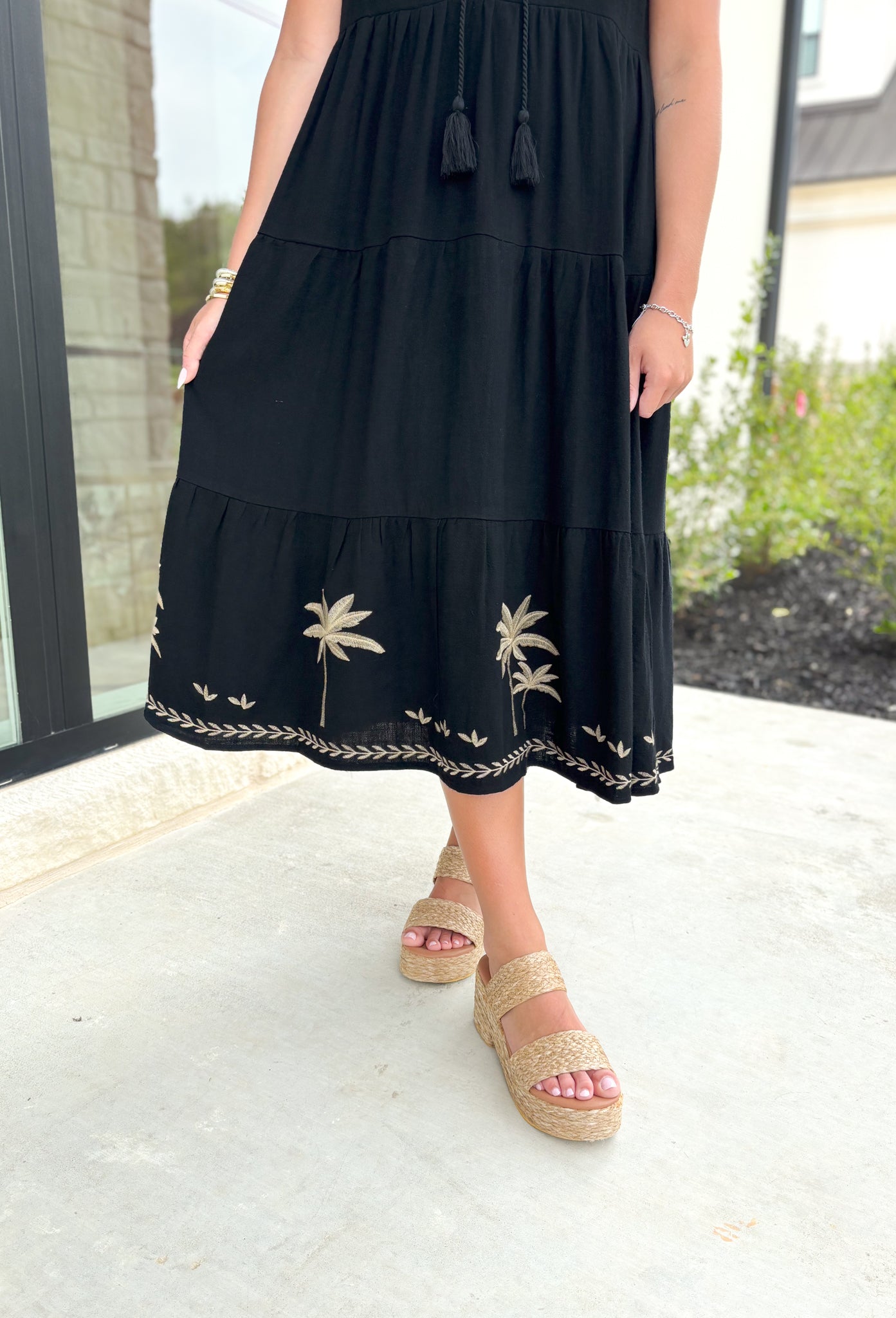 Palm Trees Please Midi Dress, black sleeveless tiered dress with v-neck, tan embroidered details around the neck and down the chest, tan embroidered palm leaves on the bottom tier of the dress 