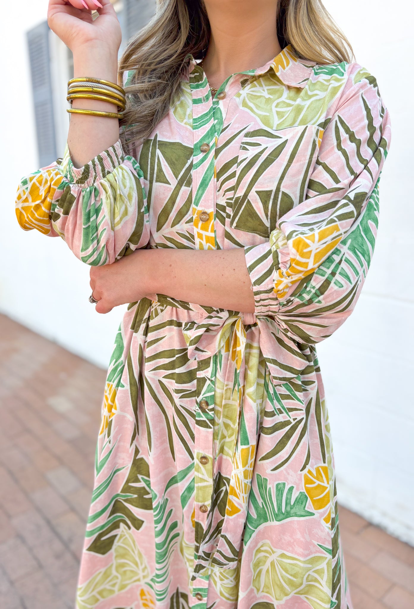 Set Me Free Midi Dress, quarter sleeve button down midi dress in a pale salmon color with sage green, amazon green and mustard yellow palm leaves printed across the dress, matching tie belt around the waist