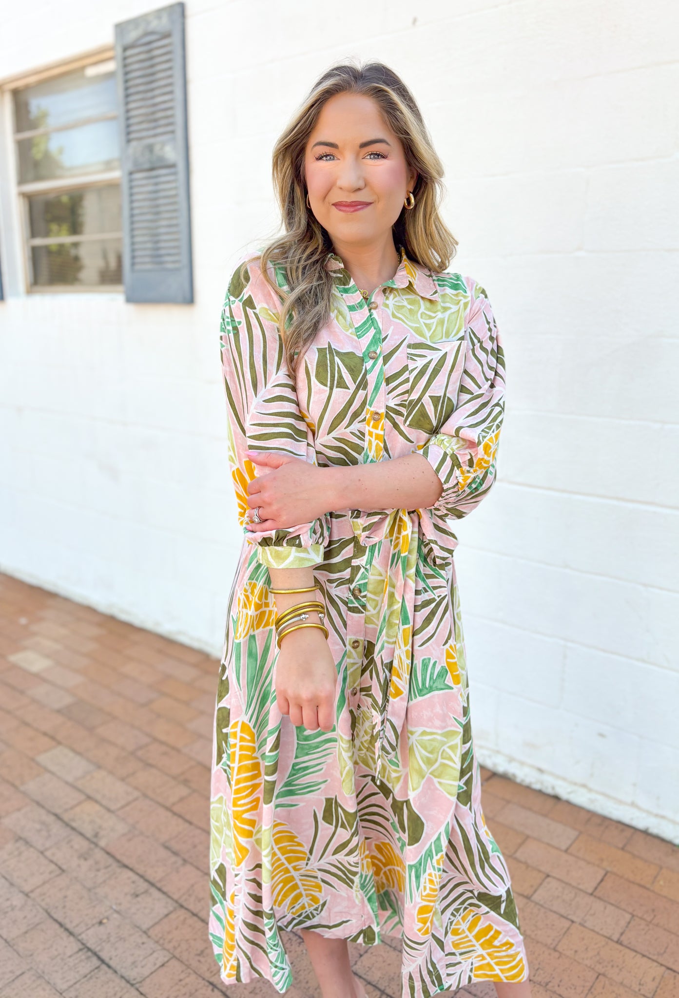 Set Me Free Midi Dress, quarter sleeve button down midi dress in a pale salmon color with sage green, amazon green and mustard yellow palm leaves printed across the dress, matching tie belt around the waist