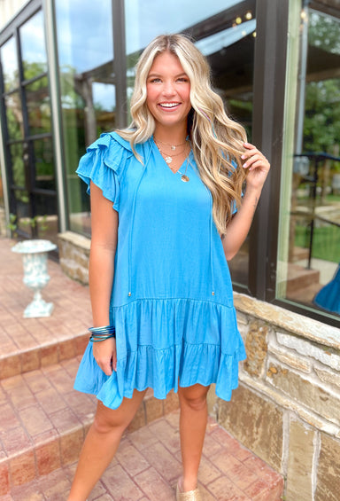 Weekends By The Coast Dress, bright blue v-neck ruffle sleeve tiered dress with string details and ruffling around the neck 