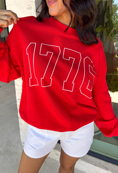A timeless nod to American pride! This red pullover features “1776” in bold white lettering across the front, making it the perfect piece to celebrate Independence Day and beyond. Classic, patriotic, and easy to style, it’s a go-to for summer holidays, fireworks, and casual days. Made from soft 100% cotton, this pullover is comfortable and breathable while still giving you that cozy feel. 