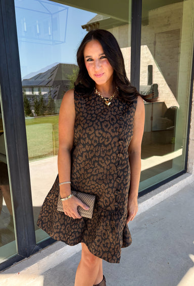Leopard gets a refined update with this black and brown printed dress from Entro. The neutral color palette gives the statement print a classic feel, making it easy to wear for everything from dinner plans and work events to fall gatherings. A full button-down detail off centered adds an unexpected touch that sets this dress apart, while the sleeveless silhouette keeps the look clean and easy to layer. The tiered skirt adds movement and shape, and the fully lined design provides comfortable coverage.