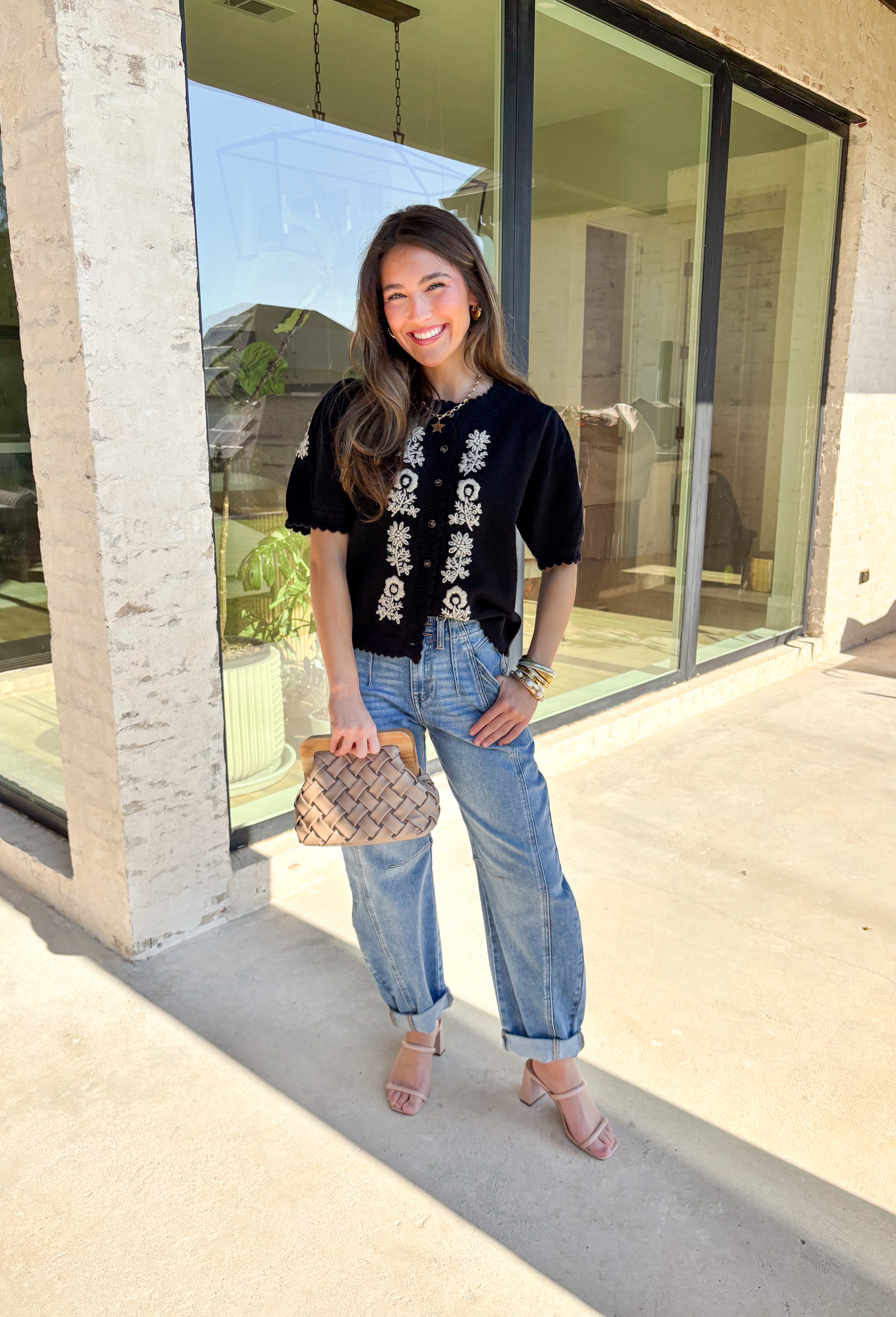 Sweet details and cozy texture make this cardigan a seasonal favorite. Designed in a soft black knit, it’s accented with cream embroidered florals down the front, and on the sleeves for a touch of charm. The scalloped trim along the sleeves, hem, and neckline adds a feminine finish, while the short sleeve and button-down design keep it versatile. An easy layering piece you can style casual or dressed up, this cardigan is the perfect balance of cozy and polished.