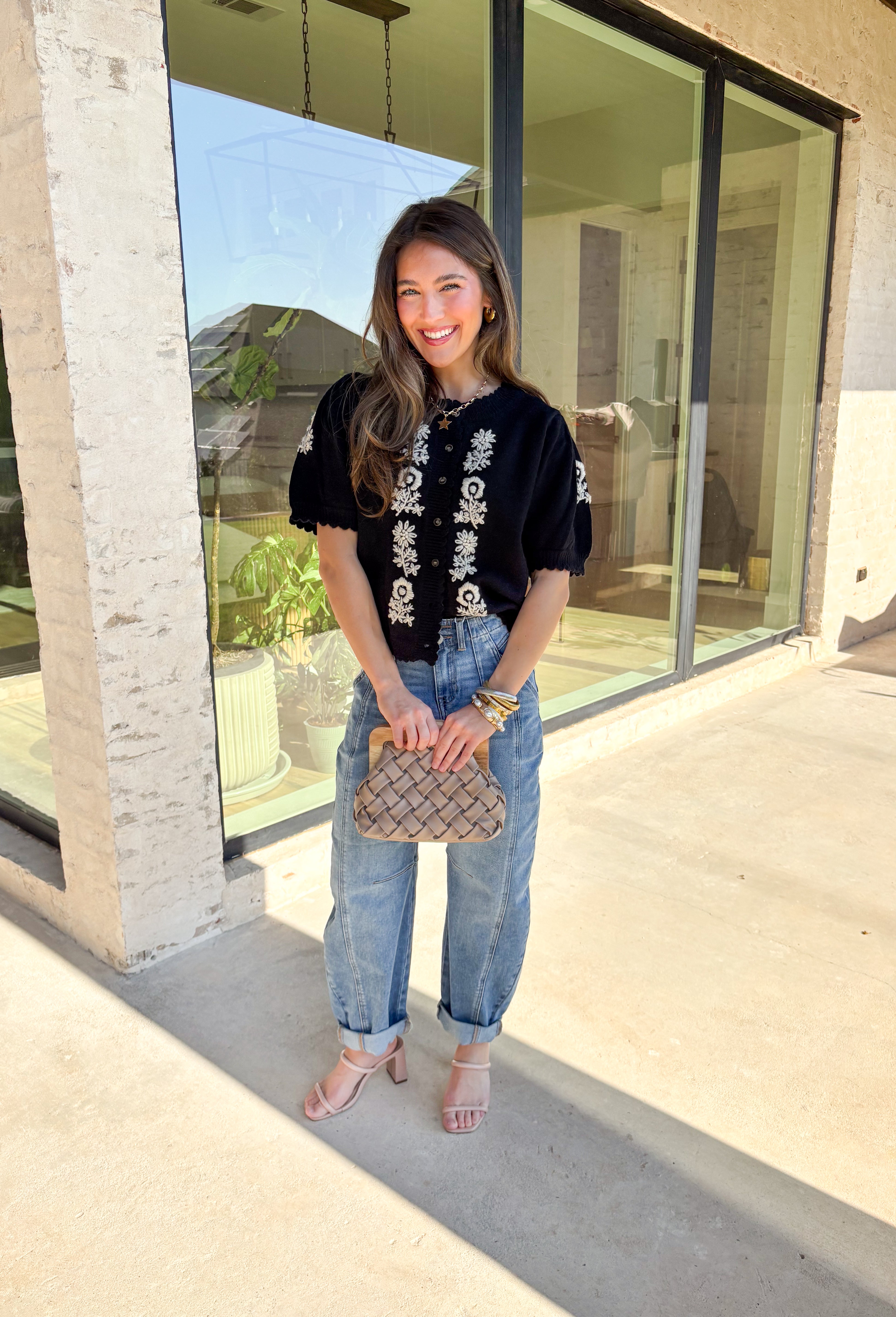 Sweet details and cozy texture make this cardigan a seasonal favorite. Designed in a soft black knit, it’s accented with cream embroidered florals down the front, and on the sleeves for a touch of charm. The scalloped trim along the sleeves, hem, and neckline adds a feminine finish, while the short sleeve and button-down design keep it versatile. An easy layering piece you can style casual or dressed up, this cardigan is the perfect balance of cozy and polished.