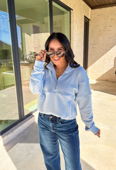 Stay warm and stylish in this light blue quarter zip pullover by Iris. Designed with a soft fleece lining, it’s as cozy as it looks. The quarter zip neckline adds versatility, while the two front pockets make it practical for everyday wear. With just the right amount of stretch in the fabric, this pullover is perfect for lounging, layering, or running errands in comfort.&nbsp;