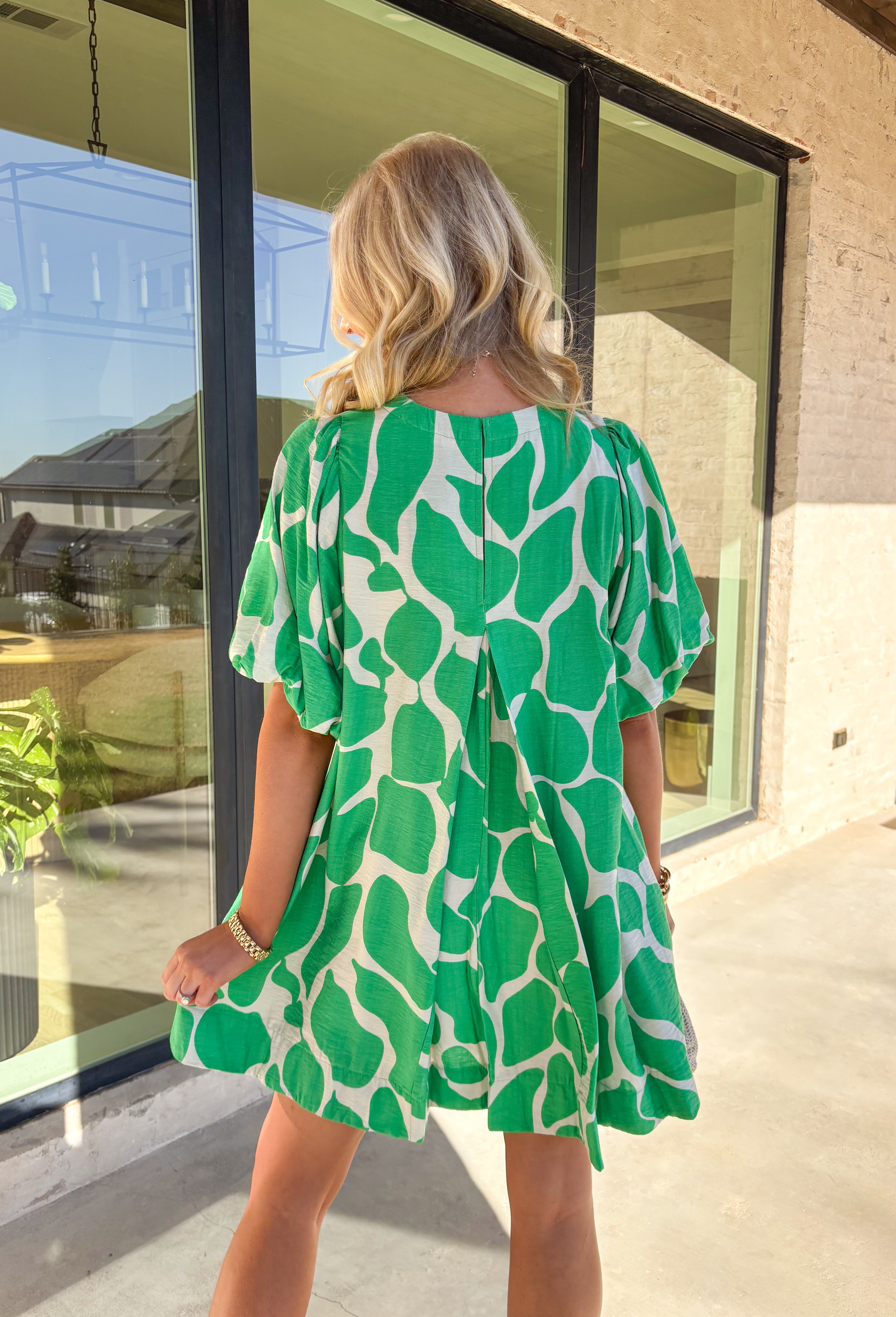 Easy, flowy, and a little artsy — this neutral dress with a bold green abstract print is ready for wherever your day takes you. Designed with puff sleeves, a breezy relaxed fit, and a sweet keyhole closure in the back, it’s the perfect mix of playful and effortless. Made by Umgee and fully lined, this dress is lightweight and comfy — aka exactly what you want for sunny days, brunch plans, or warmer weather special occasions.&nbsp;