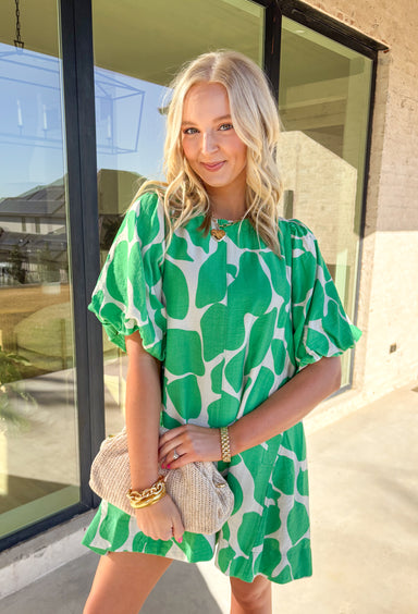 Easy, flowy, and a little artsy — this neutral dress with a bold green abstract print is ready for wherever your day takes you. Designed with puff sleeves, a breezy relaxed fit, and a sweet keyhole closure in the back, it’s the perfect mix of playful and effortless. Made by Umgee and fully lined, this dress is lightweight and comfy — aka exactly what you want for sunny days, brunch plans, or warmer weather special occasions.&nbsp;
