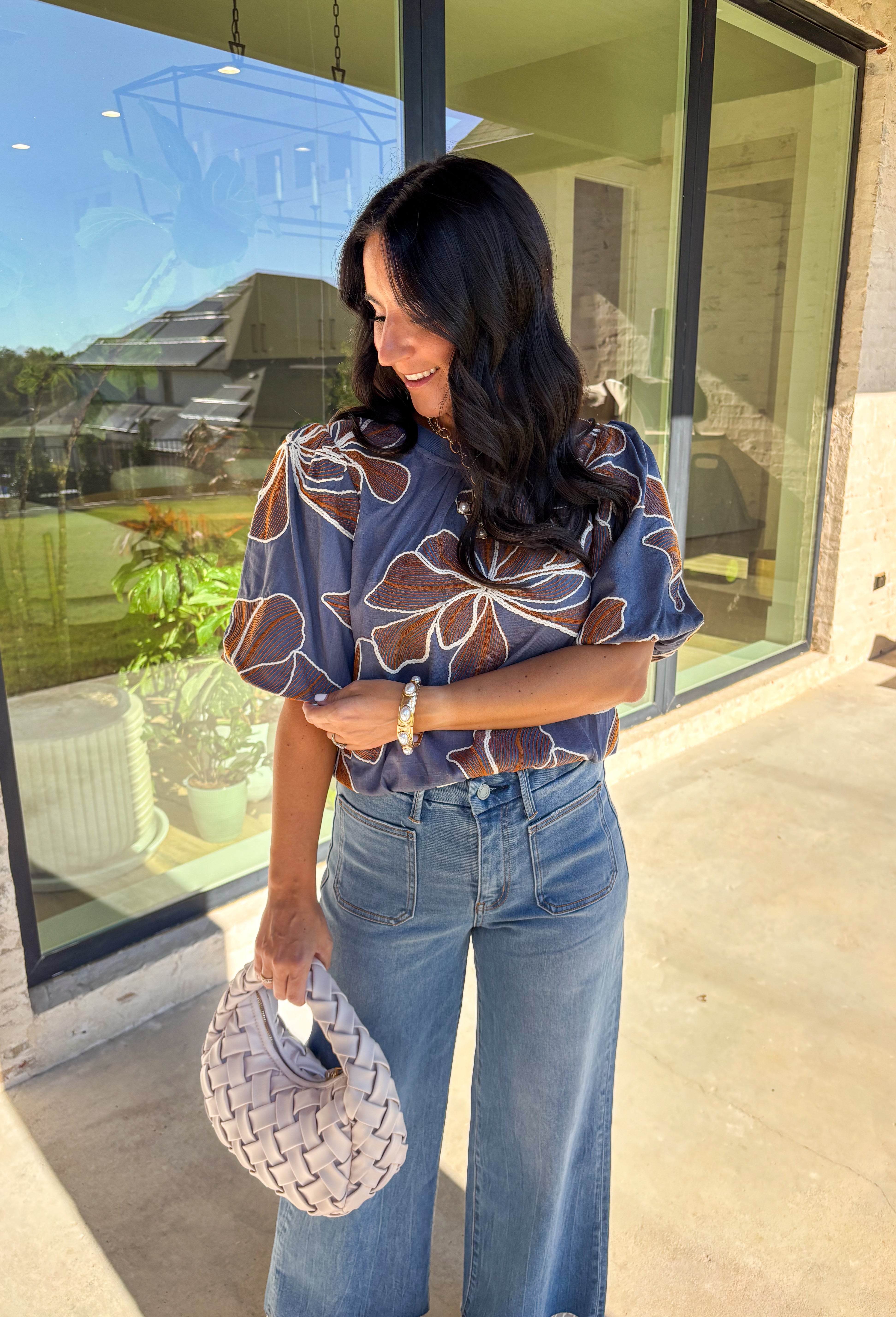 Effortlessly charming, this blue puff sleeve top by Voy is a fall favorite with a touch of whimsy. Designed with an oversized rust and white embroidered floral pattern throughout, it brings texture and color to your everyday look. The short puff sleeves and lettuce hem add a feminine finish, while the soft linen-blend fabric keeps it lightweight and breathable. Perfect for pairing with denim or skirts all season long.