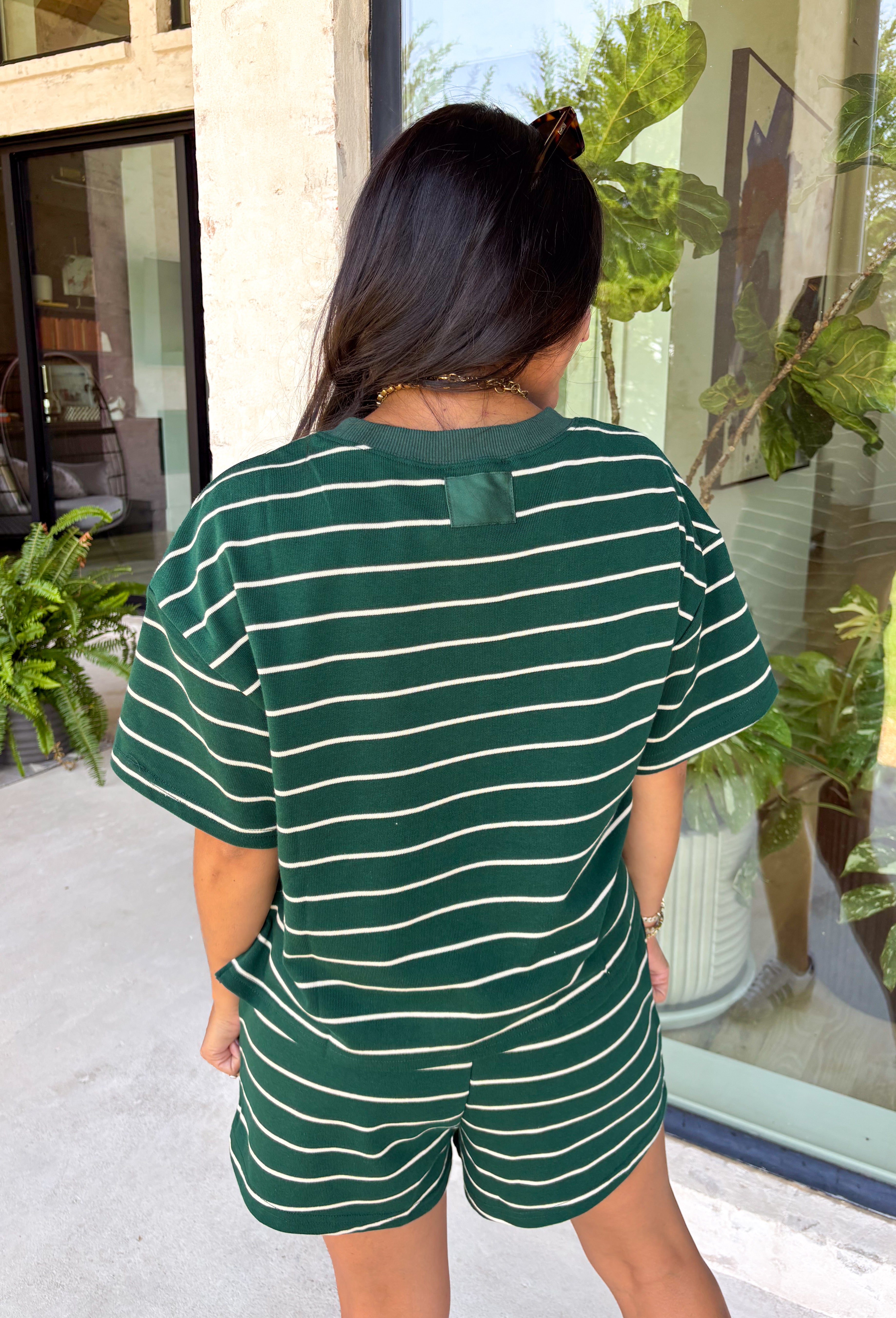Comfort meets effortless style in this hunter green striped tee. Featuring a timeless white stripe print, this soft tee is the perfect piece to take you from laid-back weekends to busy weekdays with ease. Wear it with the matching shorts for a coordinated set that's equal parts cozy and stylish, or mix and match it with your favorite denim, or leggings, for endless outfit options. 