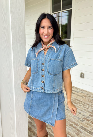 This medium wash button down denim top is one of those pieces you’ll keep reaching for all spring long! Made from 100% cotton, it’s lightweight, breathable, and perfect for layering or wearing on its own. The classic collared neckline and front pockets give it that timeless, easygoing feel, while the medium wash makes it endlessly versatile. Pair it with the matching skort for a matching set, or throw it on with white denim, skirts, —it’s the ultimate grab-and-go staple for busy days.