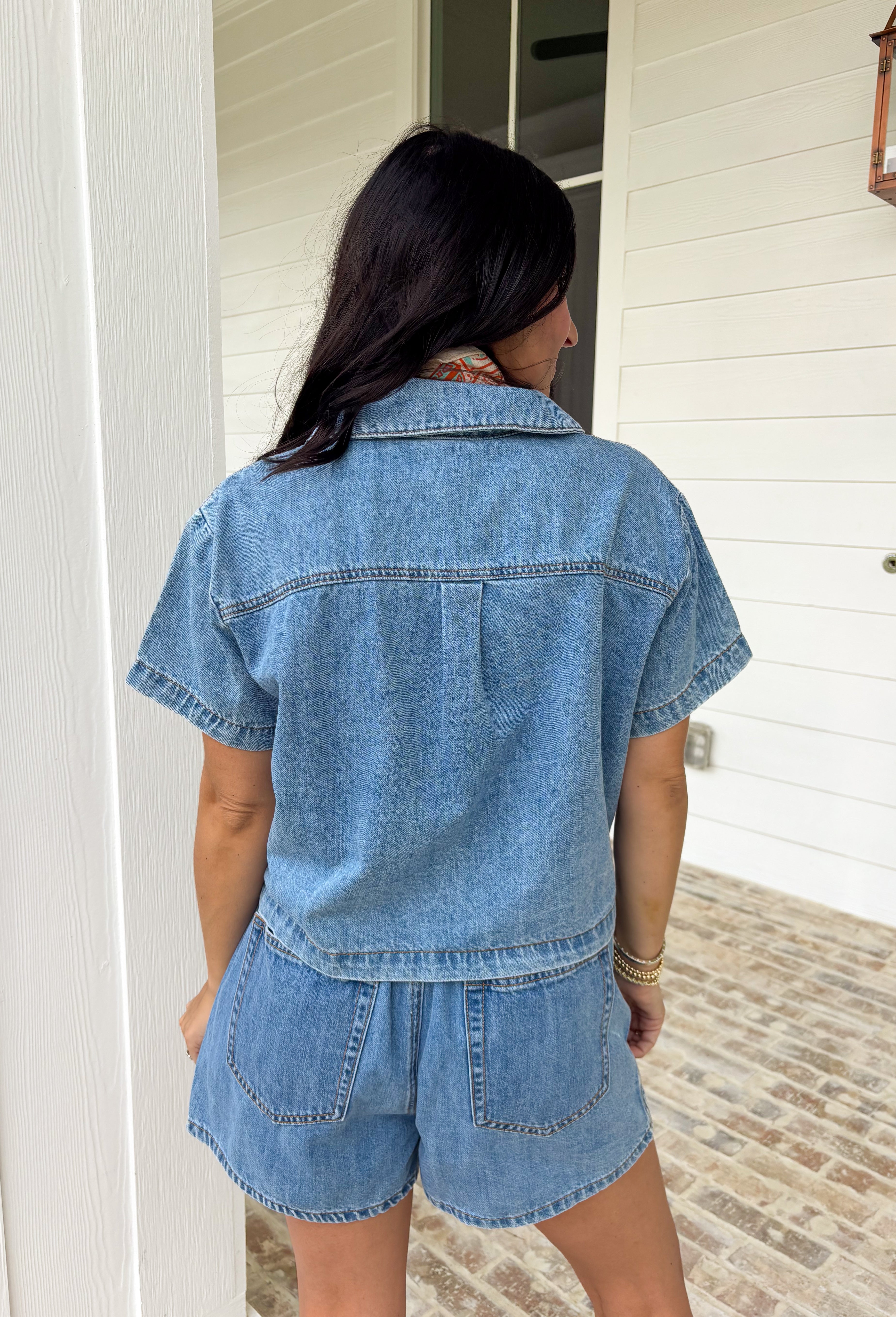 This medium wash button down denim top is one of those pieces you’ll keep reaching for all spring long! Made from 100% cotton, it’s lightweight, breathable, and perfect for layering or wearing on its own. The classic collared neckline and front pockets give it that timeless, easygoing feel, while the medium wash makes it endlessly versatile. Pair it with the matching skort for a matching set, or throw it on with white denim, skirts, —it’s the ultimate grab-and-go staple for busy days.