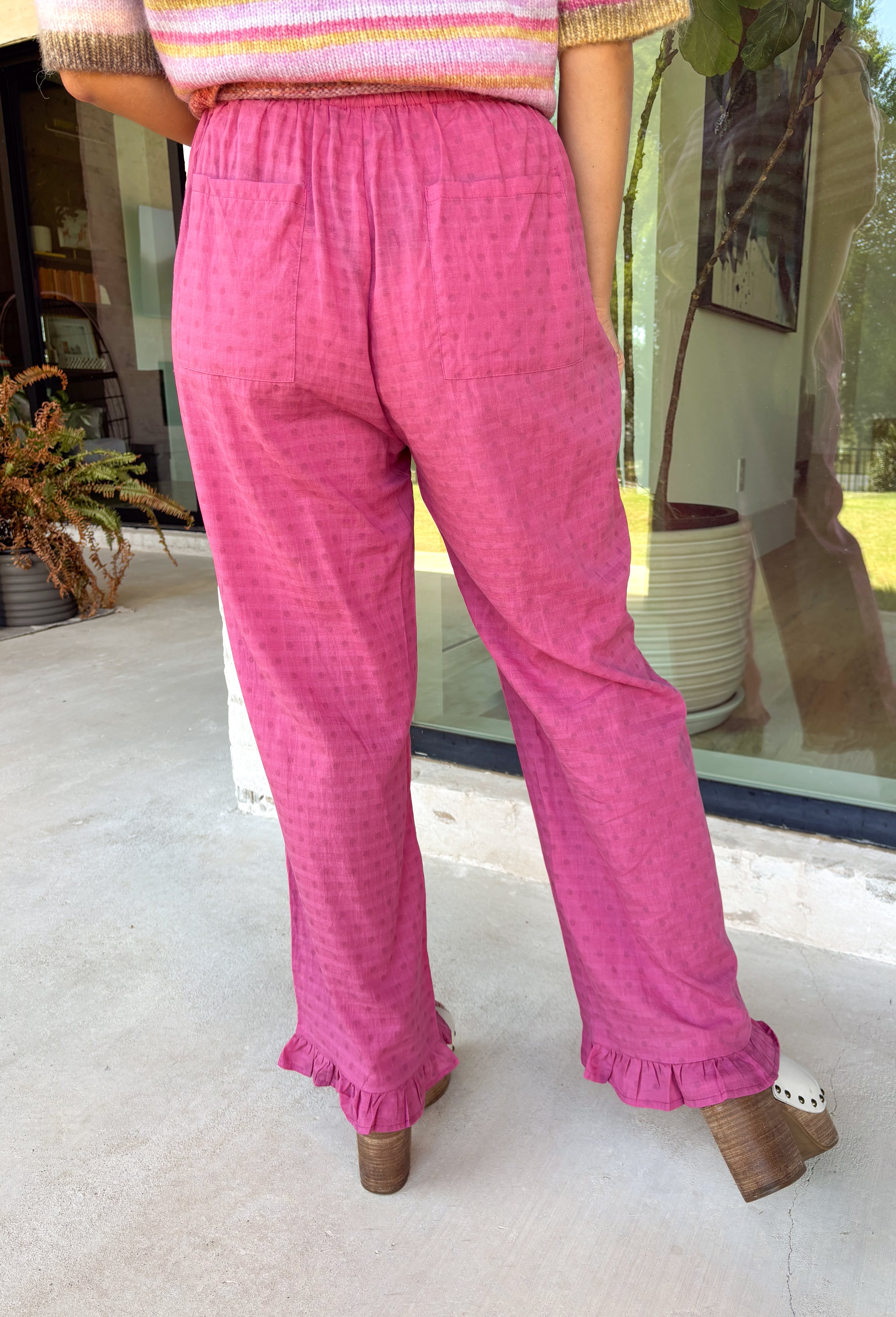 A playful pink palette gives these pants from Twentifourth plenty of personality while still keeping them easy to style. The subtle monochromatic polka dot print adds a fun touch of texture without overpowering the look, while the ruffle hem gives the relaxed silhouette a sweet finishing detail. An elastic waistband with a drawstring keeps them comfortable for all-day wear, and side and back pockets add everyday function. 