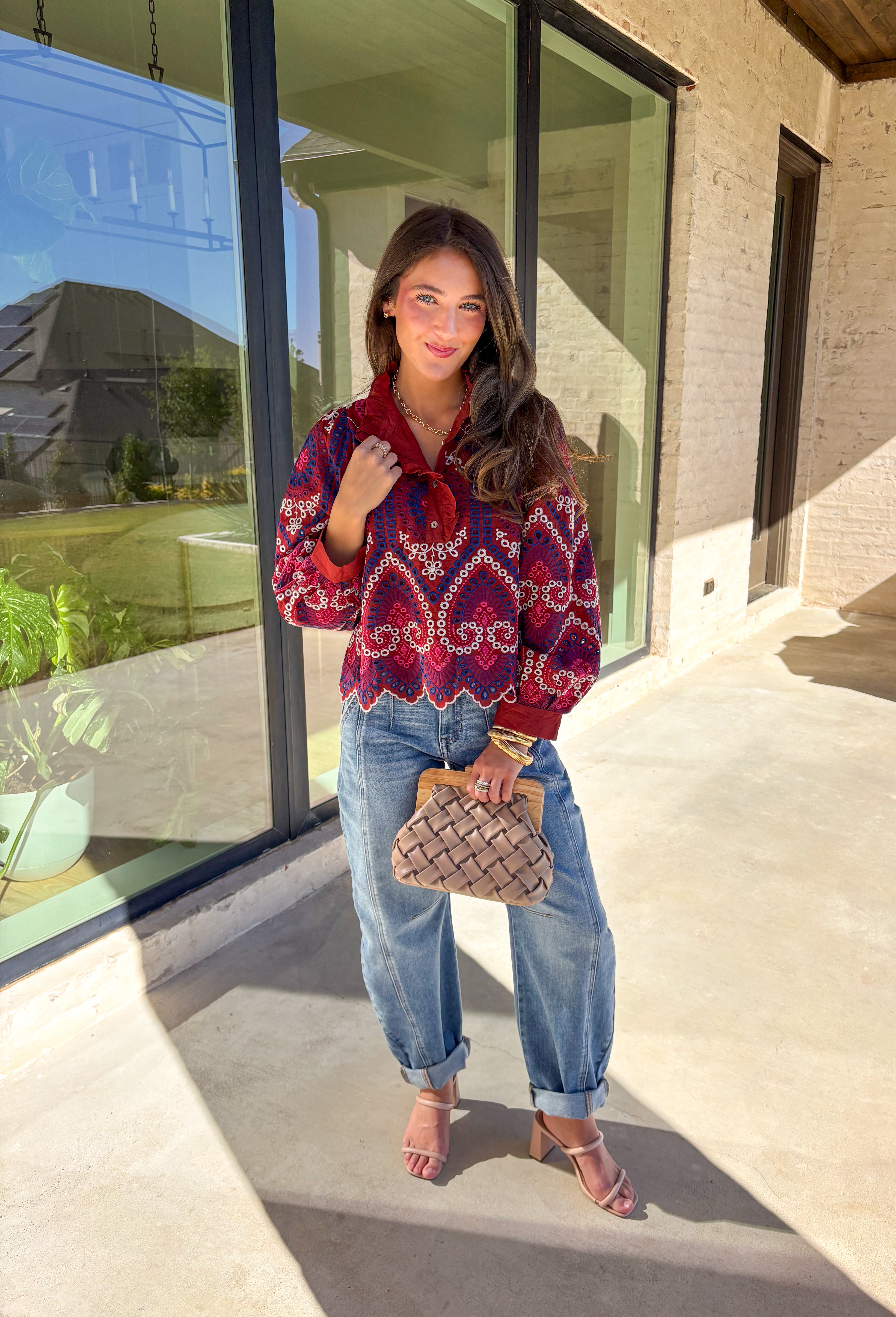 Bring color and texture to your fall wardrobe with this brick long sleeve top by Entro. The vibrant embroidered print in royal blue, white, pink, and purple adds a playful pop against the warm brick base. A ruffled neckline and trim along the front pair beautifully with the half button-down design, while the scalloped hem gives it a soft, feminine finish. Lightweight and full of detail, this top is perfect for adding a touch of boho charm to your seasonal looks.