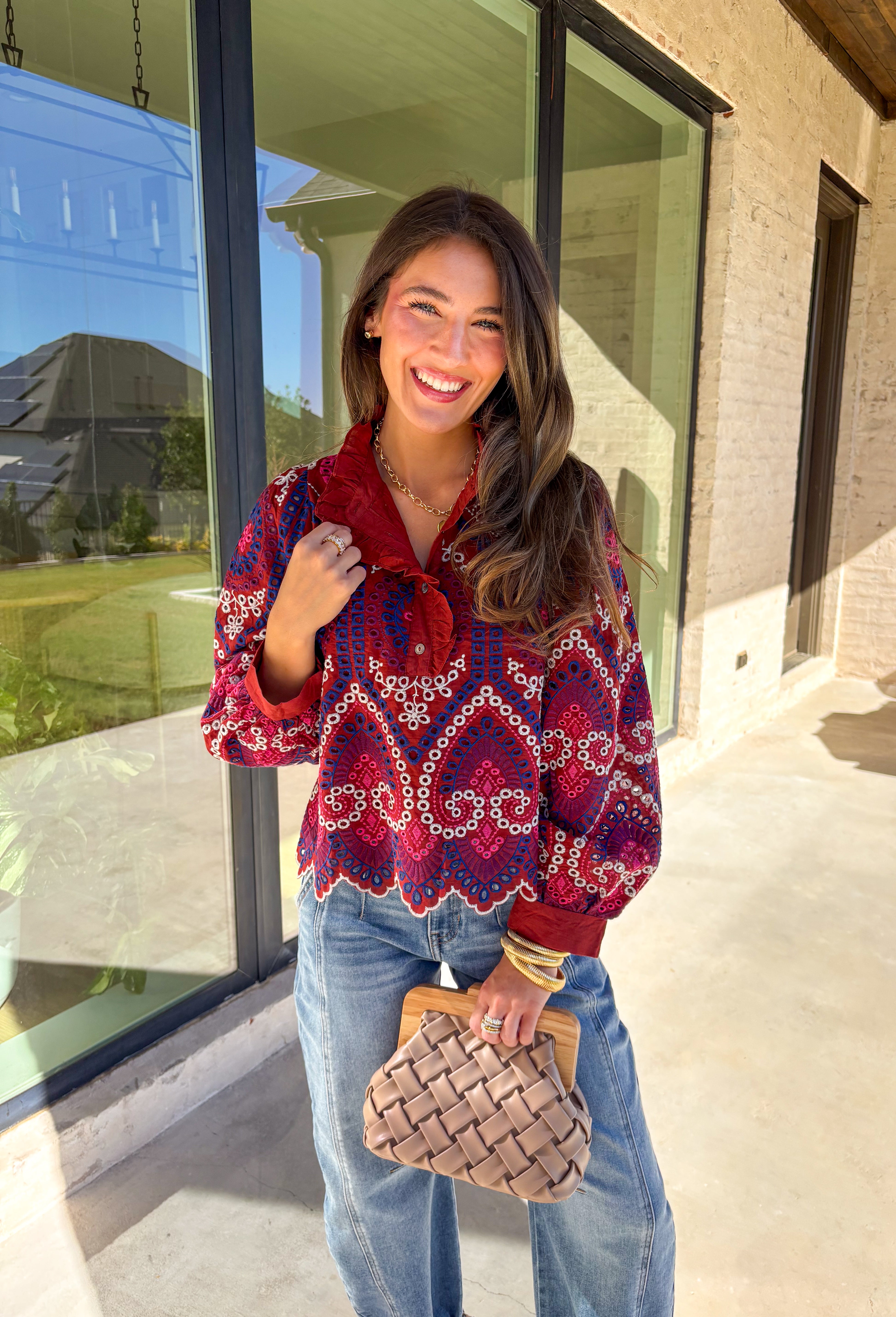 Bring color and texture to your fall wardrobe with this brick long sleeve top by Entro. The vibrant embroidered print in royal blue, white, pink, and purple adds a playful pop against the warm brick base. A ruffled neckline and trim along the front pair beautifully with the half button-down design, while the scalloped hem gives it a soft, feminine finish. Lightweight and full of detail, this top is perfect for adding a touch of boho charm to your seasonal looks.