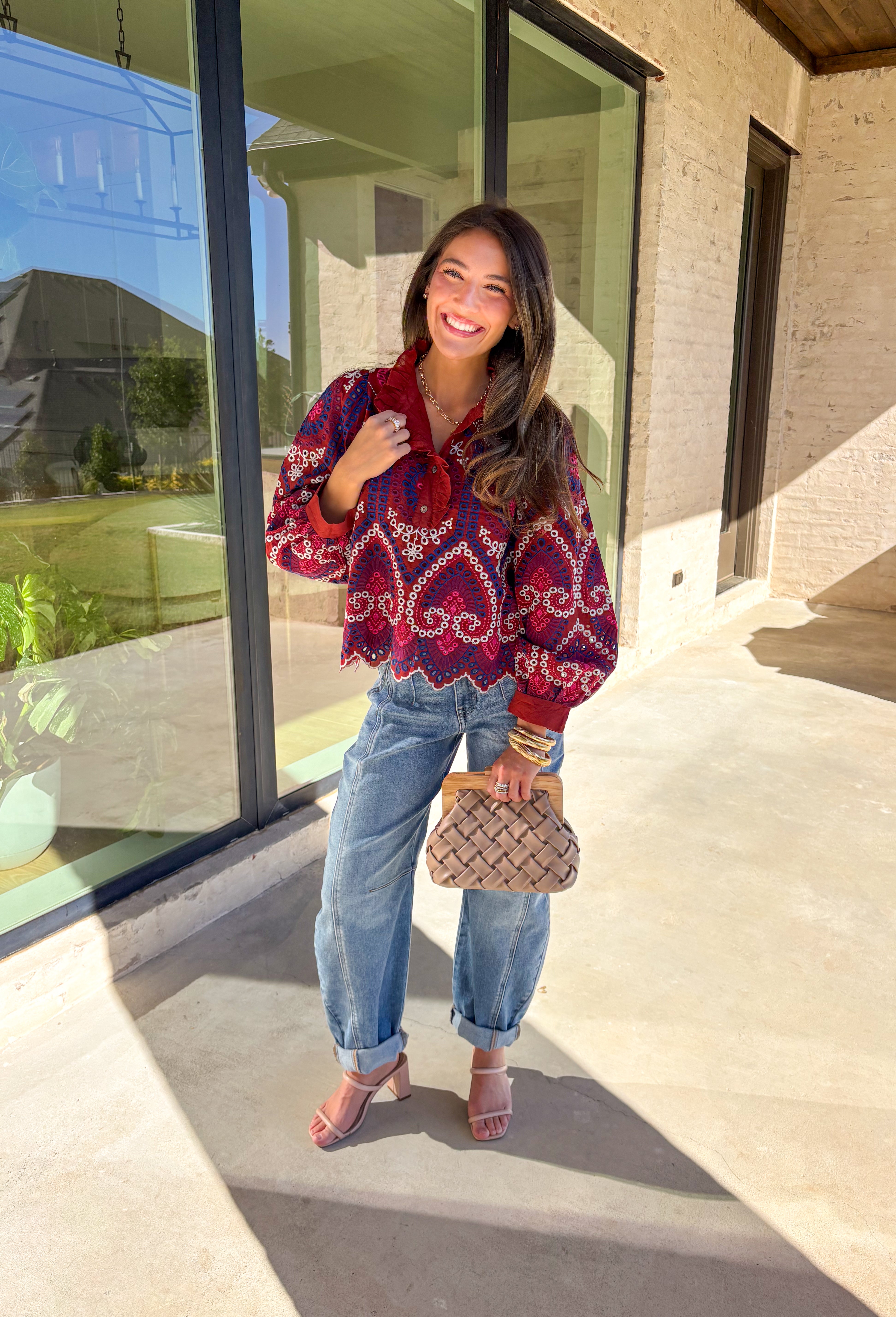 Bring color and texture to your fall wardrobe with this brick long sleeve top by Entro. The vibrant embroidered print in royal blue, white, pink, and purple adds a playful pop against the warm brick base. A ruffled neckline and trim along the front pair beautifully with the half button-down design, while the scalloped hem gives it a soft, feminine finish. Lightweight and full of detail, this top is perfect for adding a touch of boho charm to your seasonal looks.