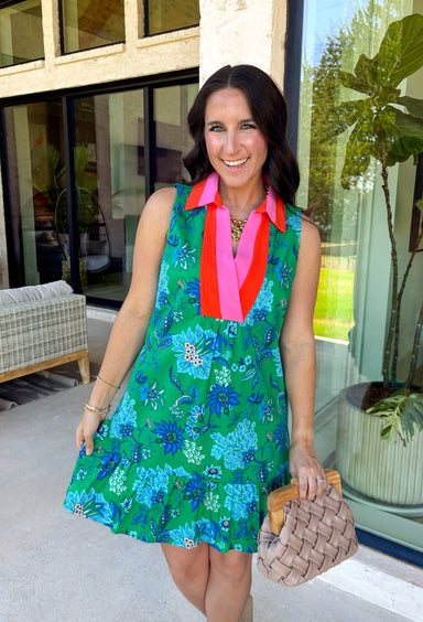 Fresh, vibrant, and made for sunny days, this sleeveless green dress is blooming with a beautiful blue floral print that instantly brightens your look. The pink and tomato red contrast trim along the collared neckline and along the front adds a playful pop of color that makes this piece feel extra special. It’s the kind of dress you’ll reach for when you want something easy, flattering, and full of personality.