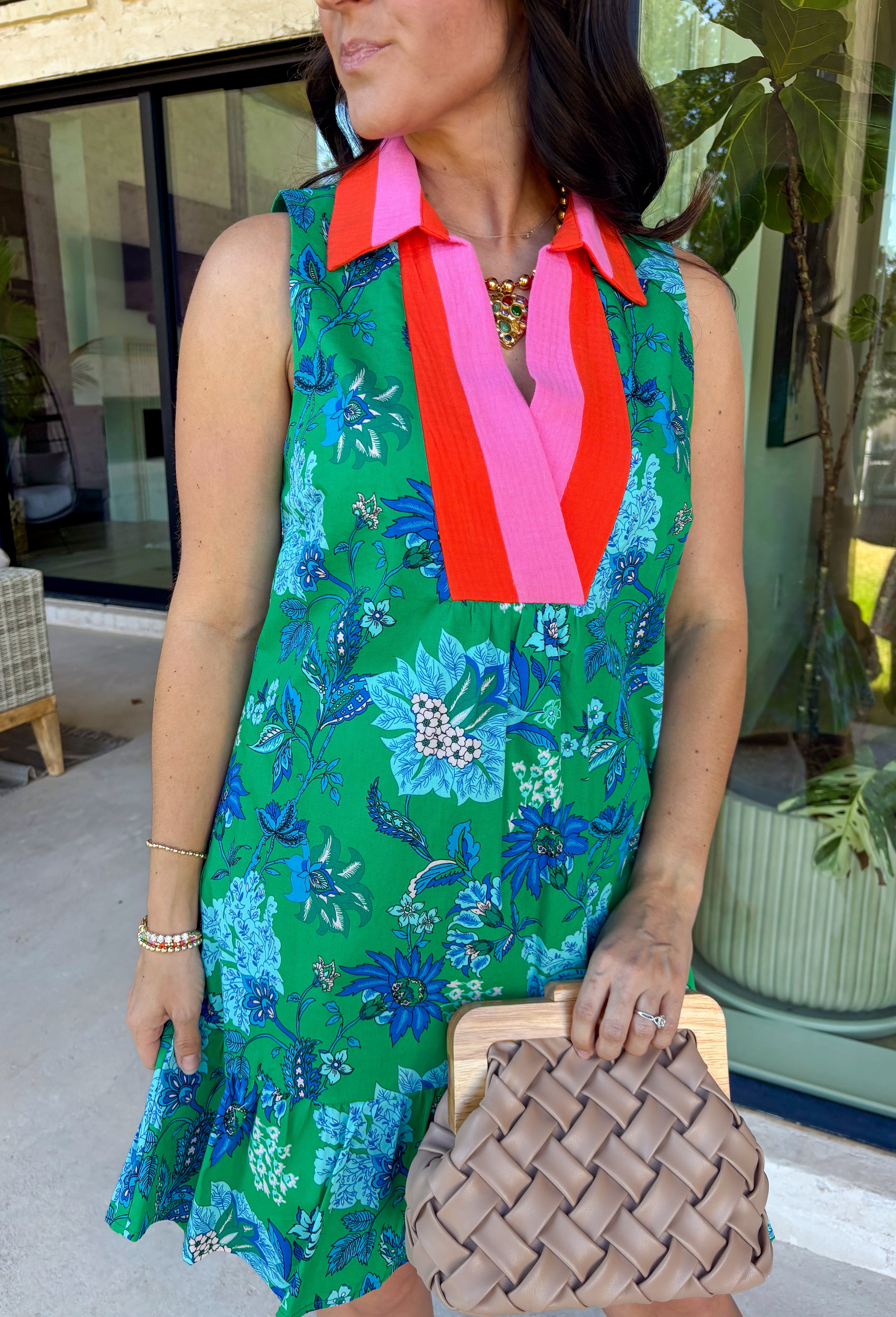 Fresh, vibrant, and made for sunny days, this sleeveless green dress is blooming with a beautiful blue floral print that instantly brightens your look. The pink and tomato red contrast trim along the collared neckline and along the front adds a playful pop of color that makes this piece feel extra special. It’s the kind of dress you’ll reach for when you want something easy, flattering, and full of personality.