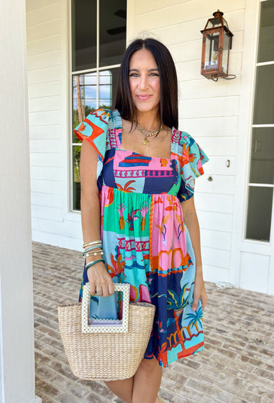This light blue dress is bringing all the tropical energy in the prettiest way. Featuring a colorful abstract print with pops of green, navy, orange, and pink, it feels fresh, vibrant, and ready for sunshine. The square neckline adds a flattering, modern touch, while the elastic sleeves give it that soft, feminine shape we love. A smocked back ensures a comfortable, flexible fit, and the fully lined design keeps it easy to wear all day long. 