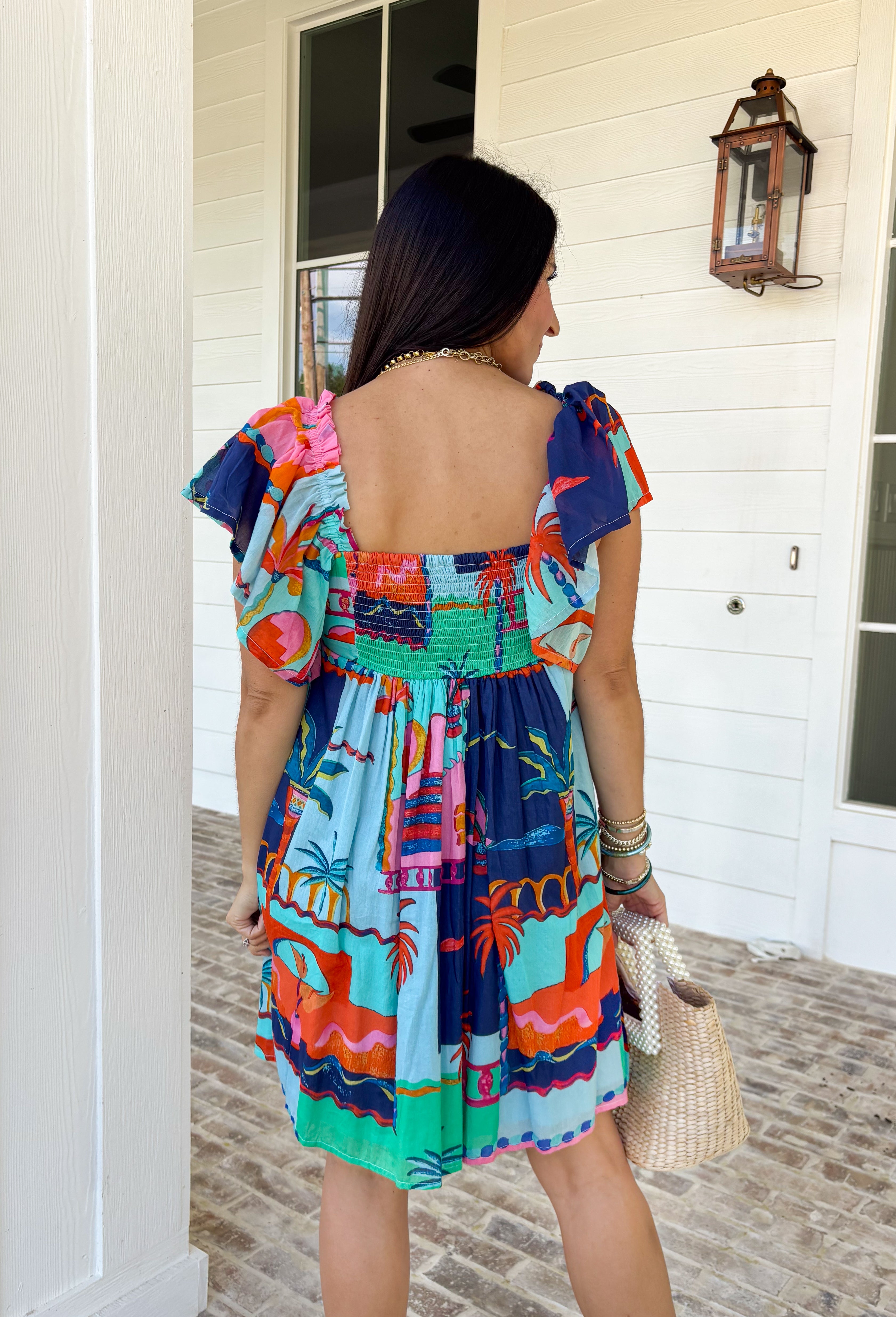 This light blue dress is bringing all the tropical energy in the prettiest way. Featuring a colorful abstract print with pops of green, navy, orange, and pink, it feels fresh, vibrant, and ready for sunshine. The square neckline adds a flattering, modern touch, while the elastic sleeves give it that soft, feminine shape we love. A smocked back ensures a comfortable, flexible fit, and the fully lined design keeps it easy to wear all day long. 