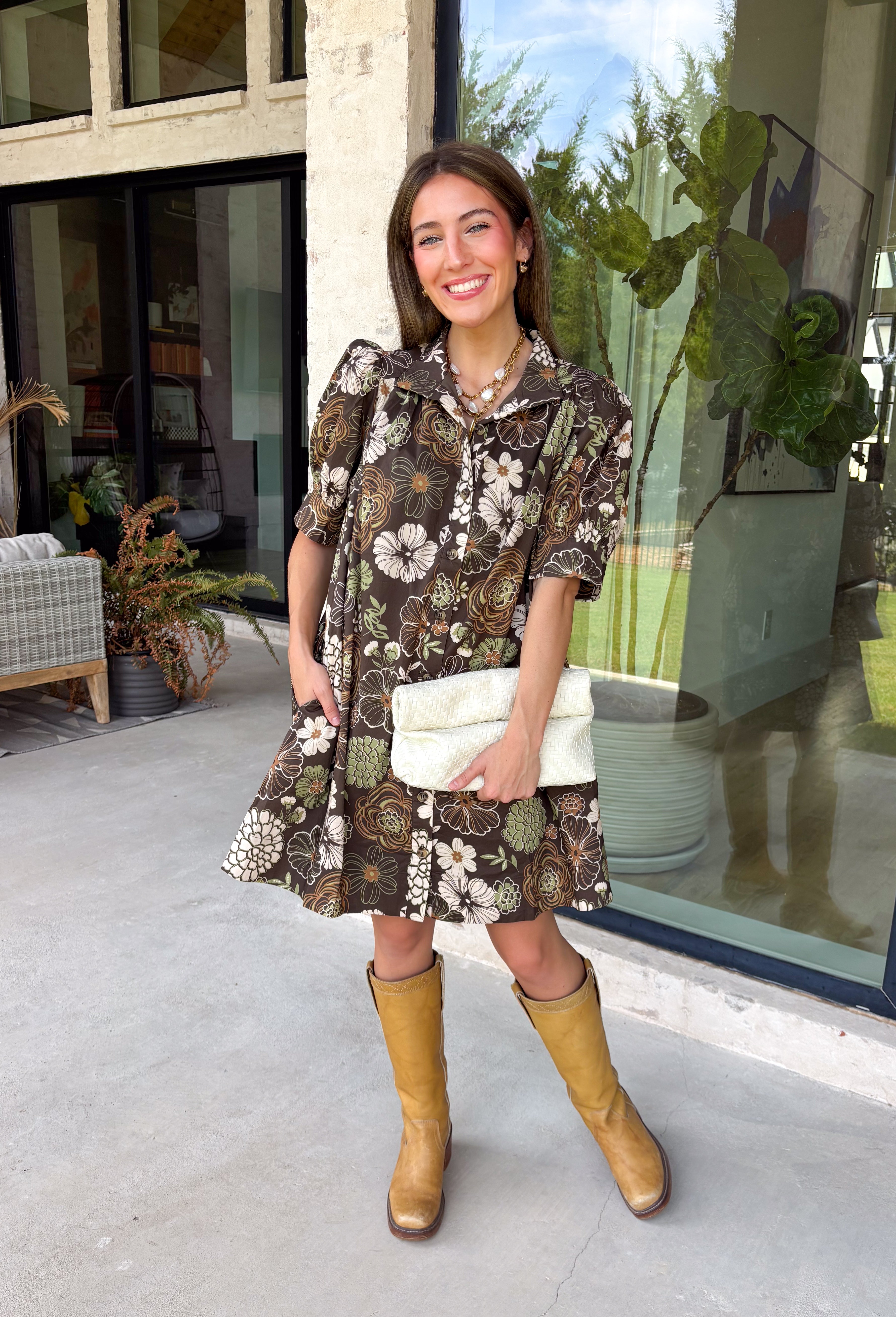 Warm autumn shades make this floral dress from Entro an easy pick for all your fall plans. The rich brown background is paired with a neutral floral print, creating a seasonal look that works beautifully for family photos, brunch, church, and weekend gatherings. A classic shirt collar and button-front closure give it a put-together feel, while short puff sleeves add just the right amount of shape. Pleated detailing at the back brings an unexpected touch to the silhouette.