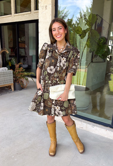 Warm autumn shades make this floral dress from Entro an easy pick for all your fall plans. The rich brown background is paired with a neutral floral print, creating a seasonal look that works beautifully for family photos, brunch, church, and weekend gatherings. A classic shirt collar and button-front closure give it a put-together feel, while short puff sleeves add just the right amount of shape. Pleated detailing at the back brings an unexpected touch to the silhouette.